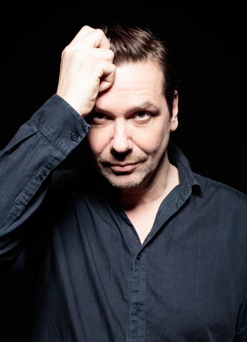 Portrait von Michael Maertens mit Hand am Kopf vor strukturierter Wand