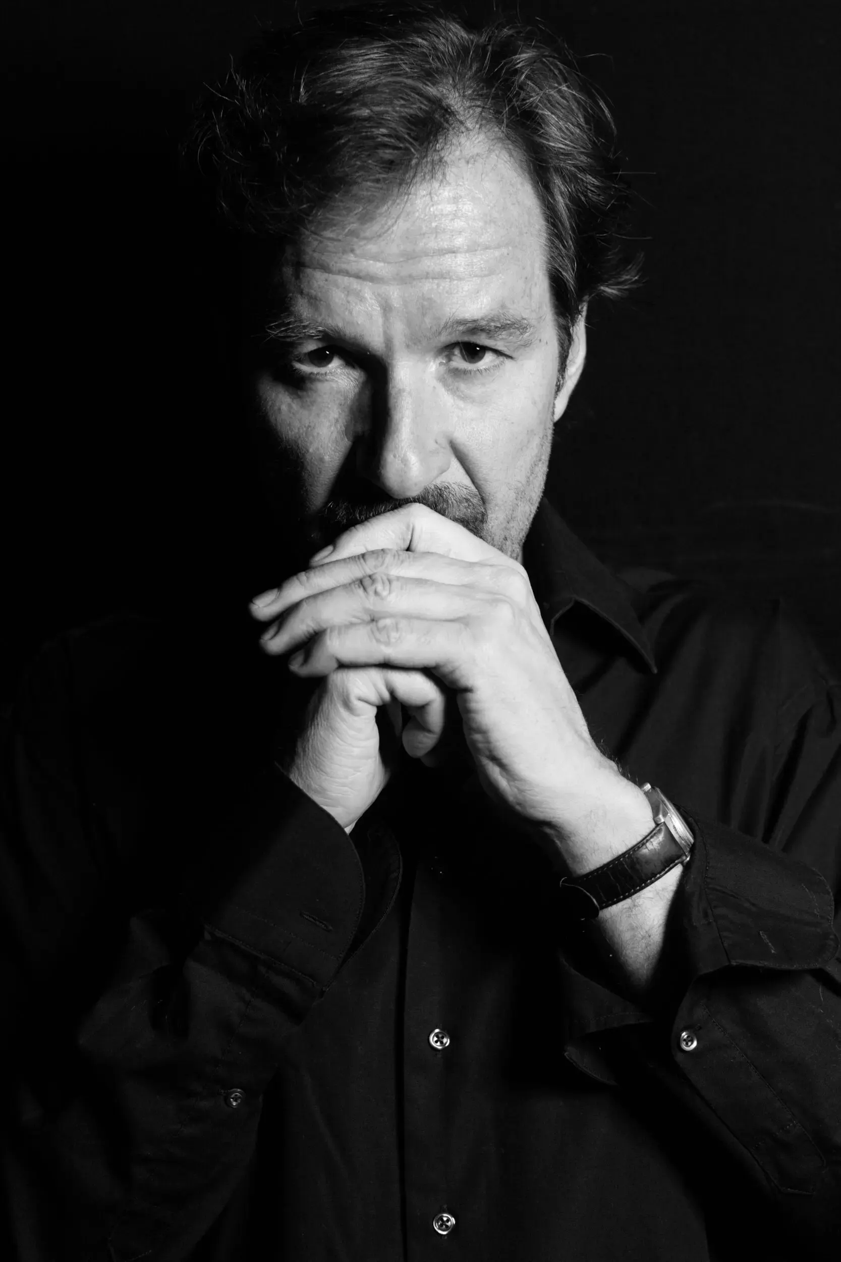 Schwarzweissportrait von Michael Neuenschwander mit gefalteten Händen am Kinn