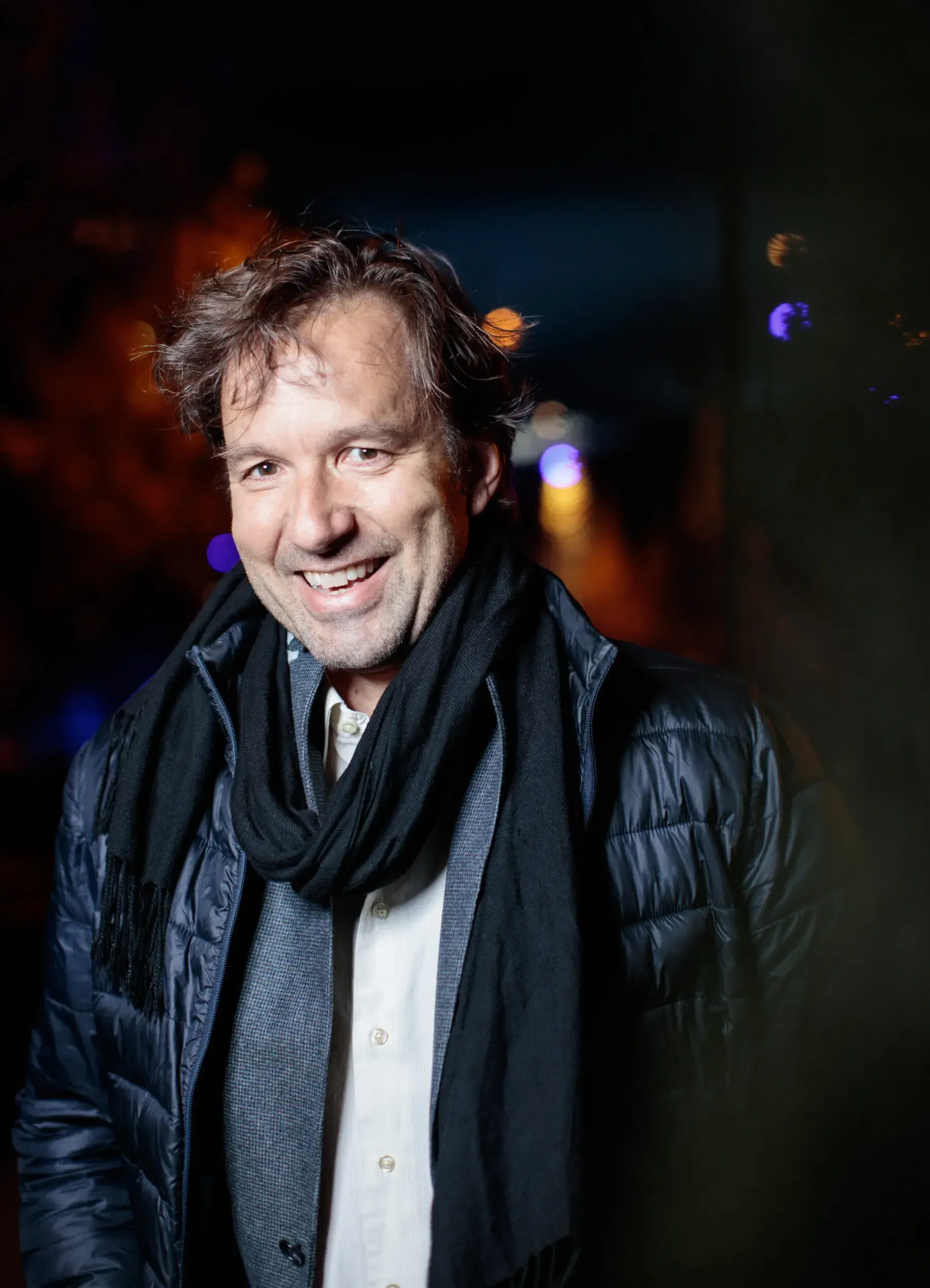 Portrait von Michael Neuenschwander bei Nacht mit Lichtern im Hintergrund