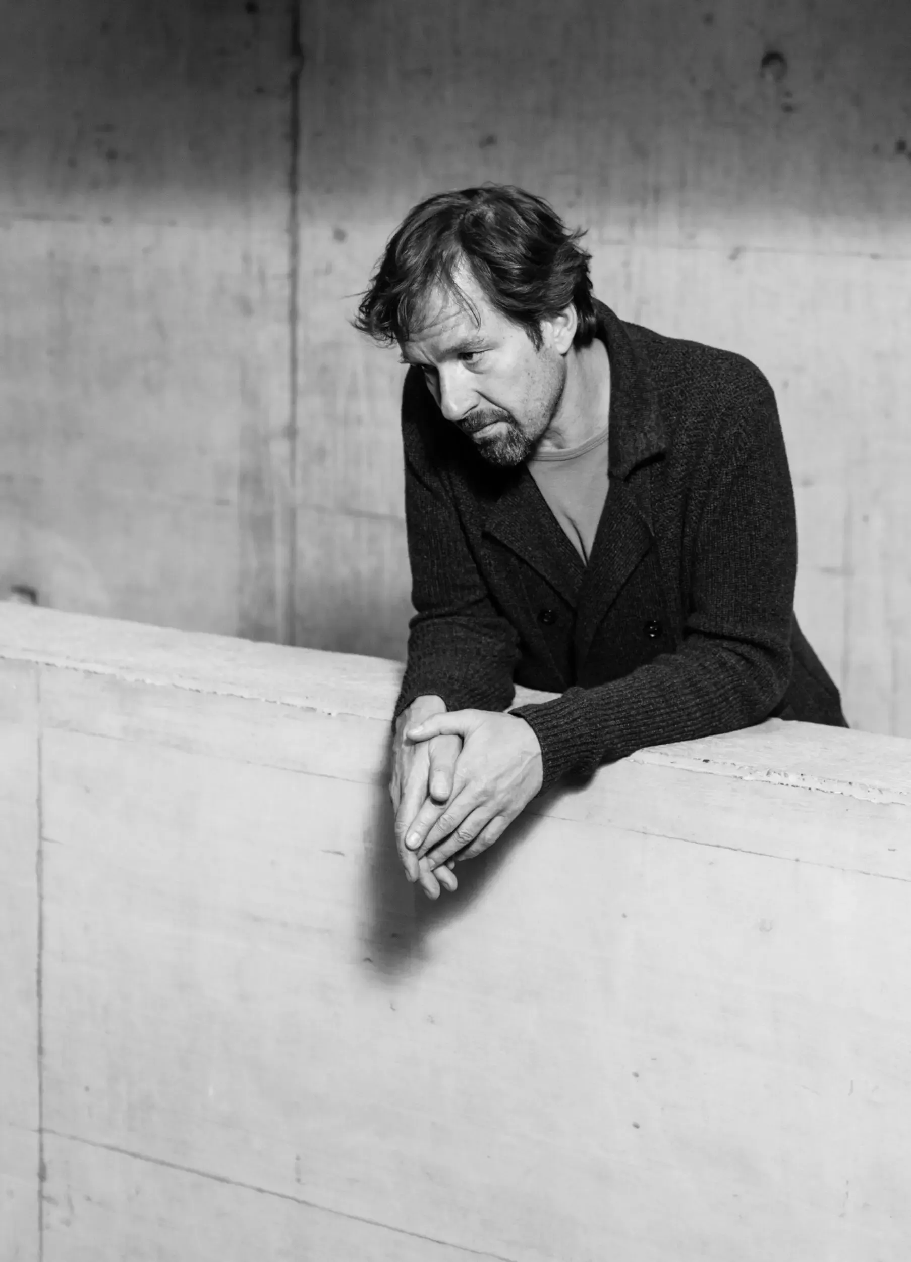 Schwarzweissportrait: Michael Neuenschwander lehnt an einer Betonmauer