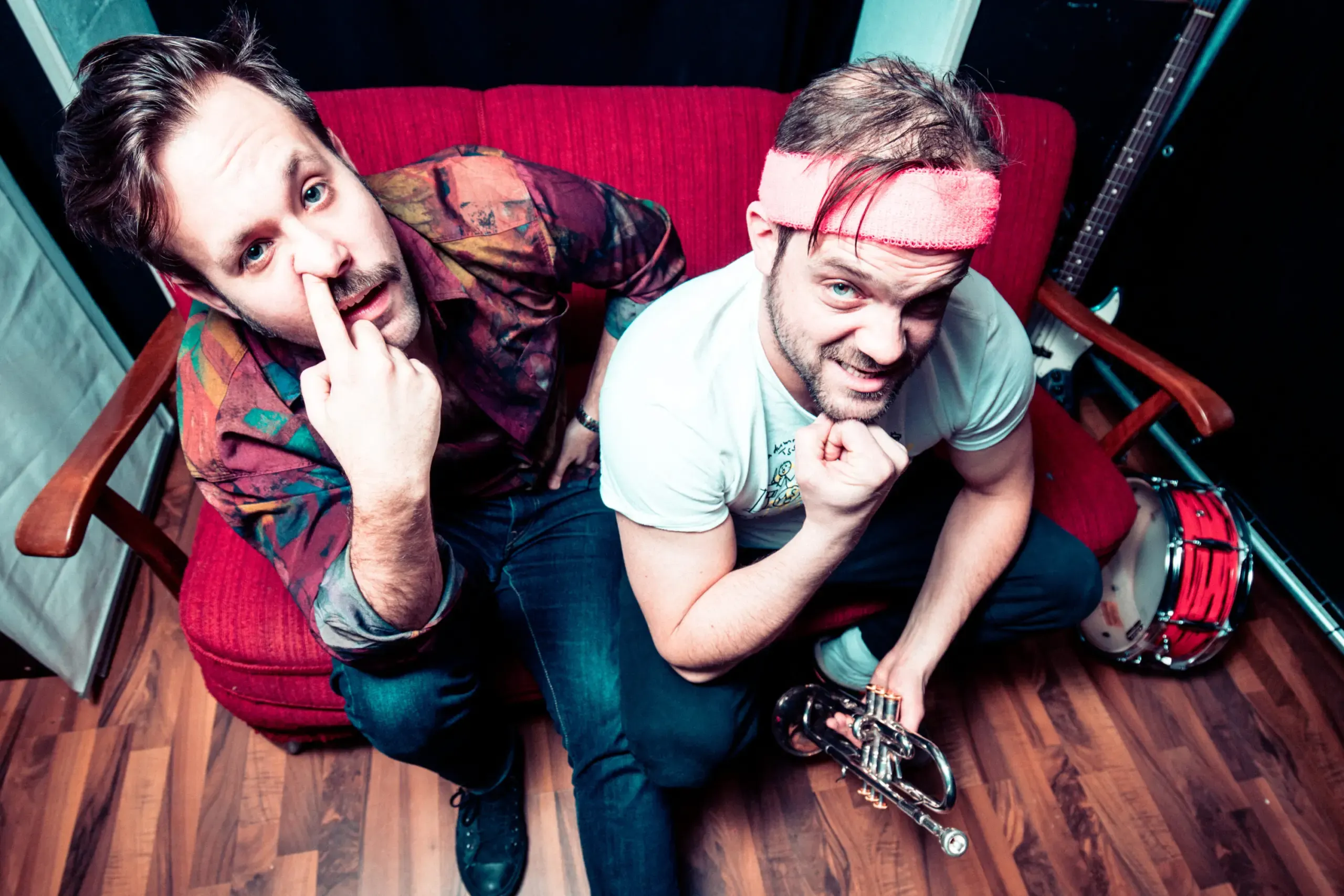 Bandduo macht Grimassen auf rotem Sofa