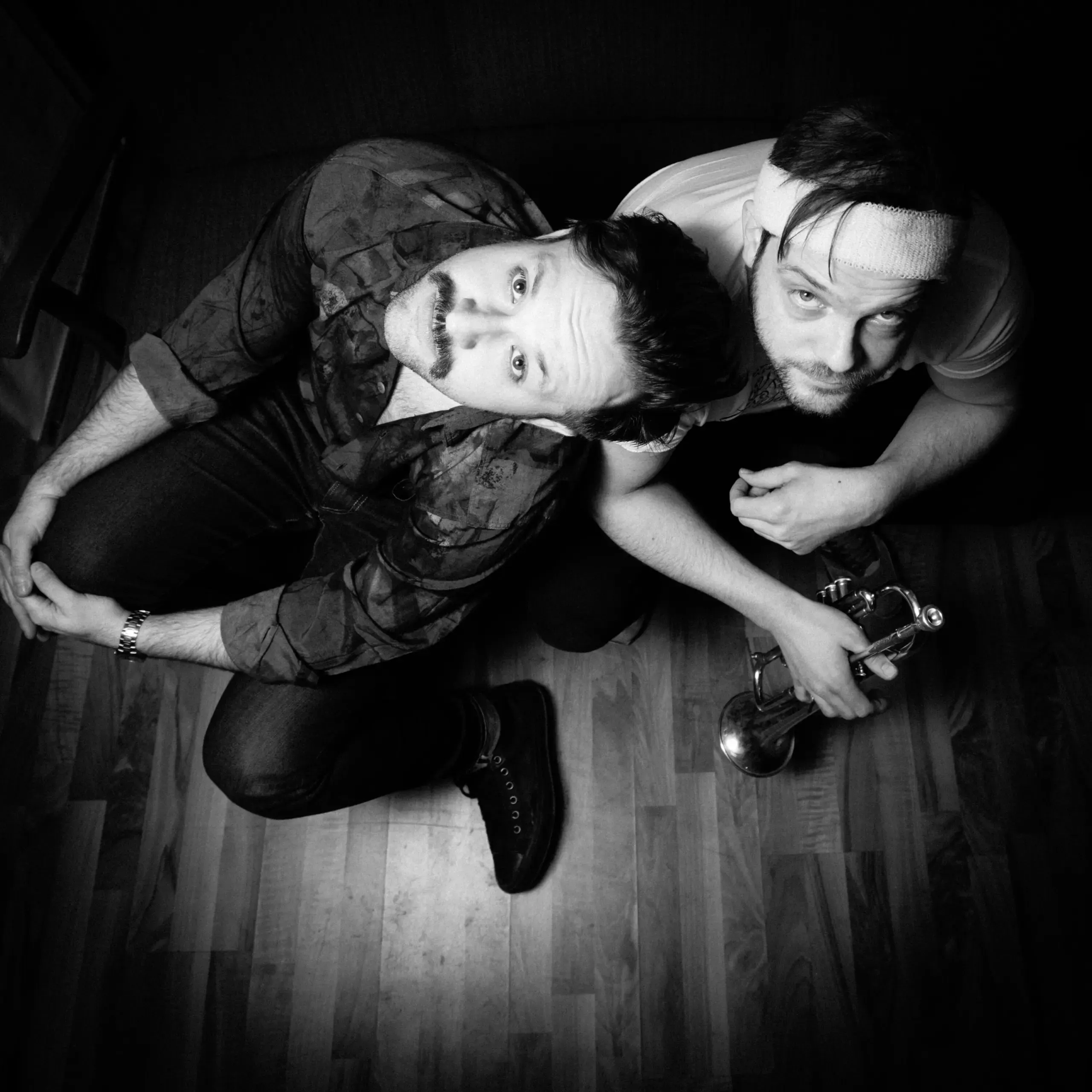 Schwarzweissfoto: Bandduo liegt eng zusammen am Boden