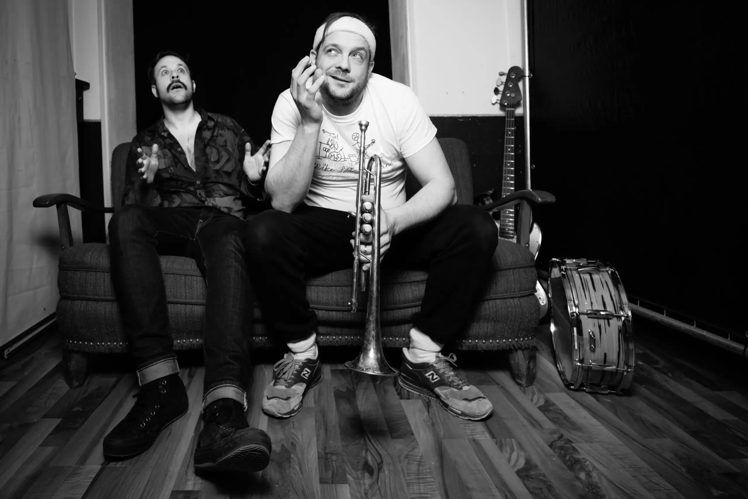 Schwarzweissfoto: Duo mit Trompete auf dem Sofa, entspannte Pose
