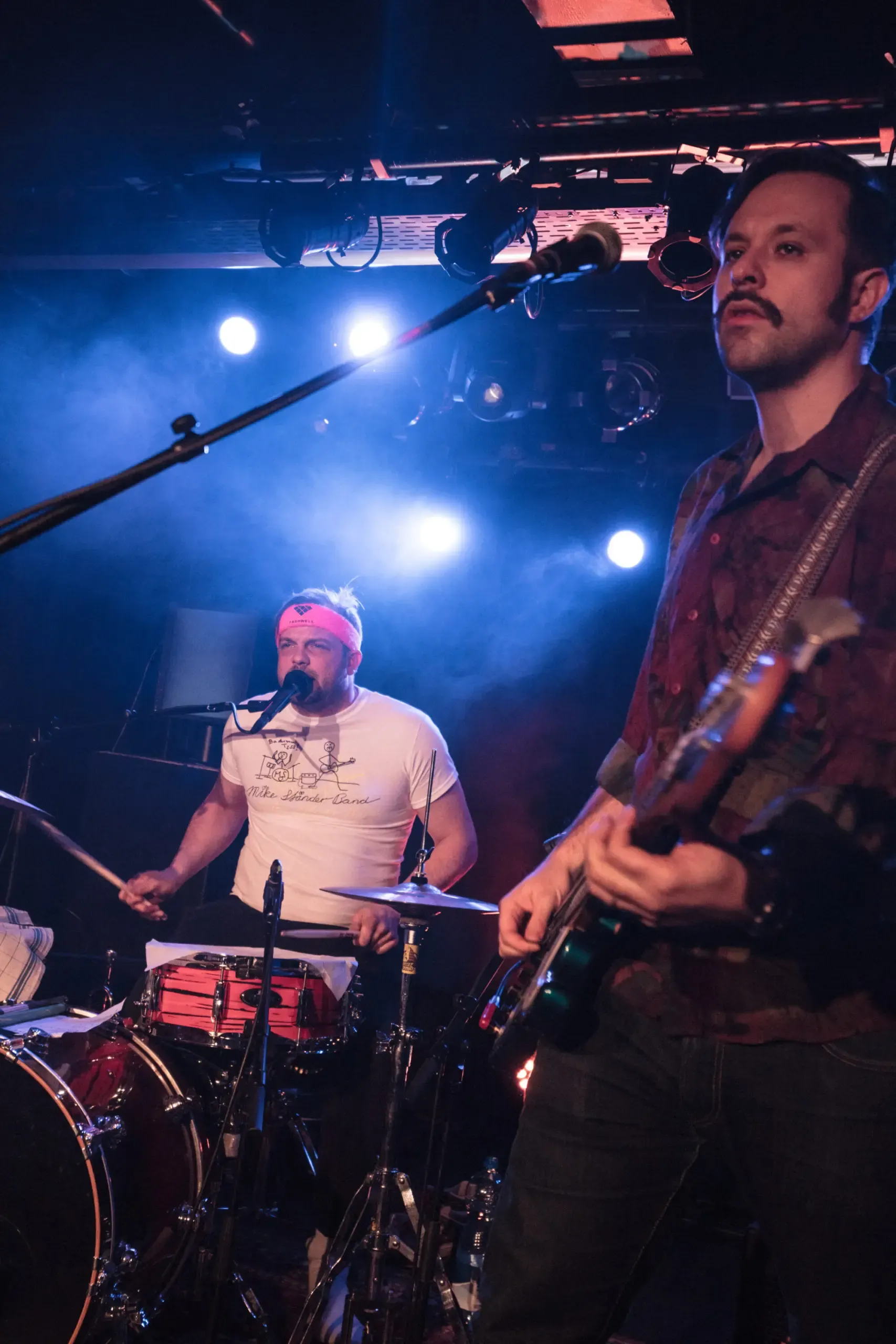 Mike-Ständer-Band-Mitglieder mit Schlagzeug und Gitarre auf der Bühne