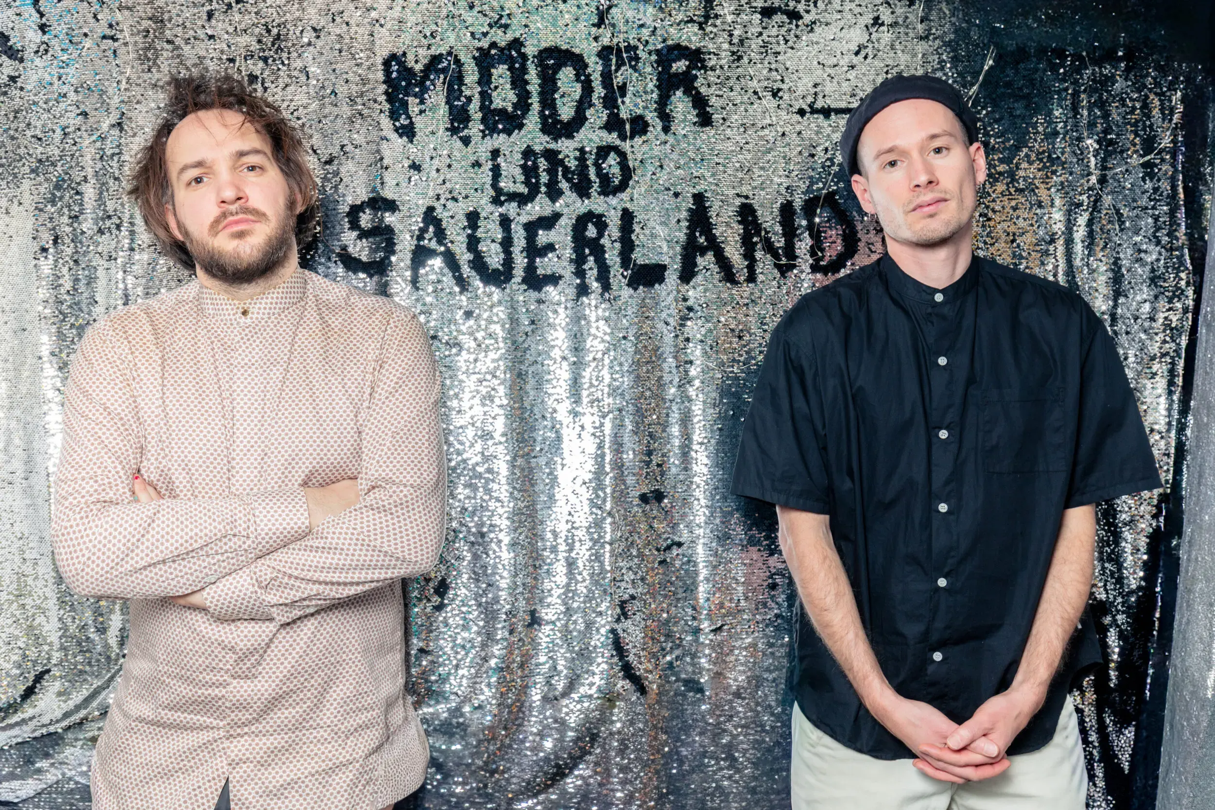 Moder und Sauerland stehen vor einer Wand mit ihrem Bandnamen