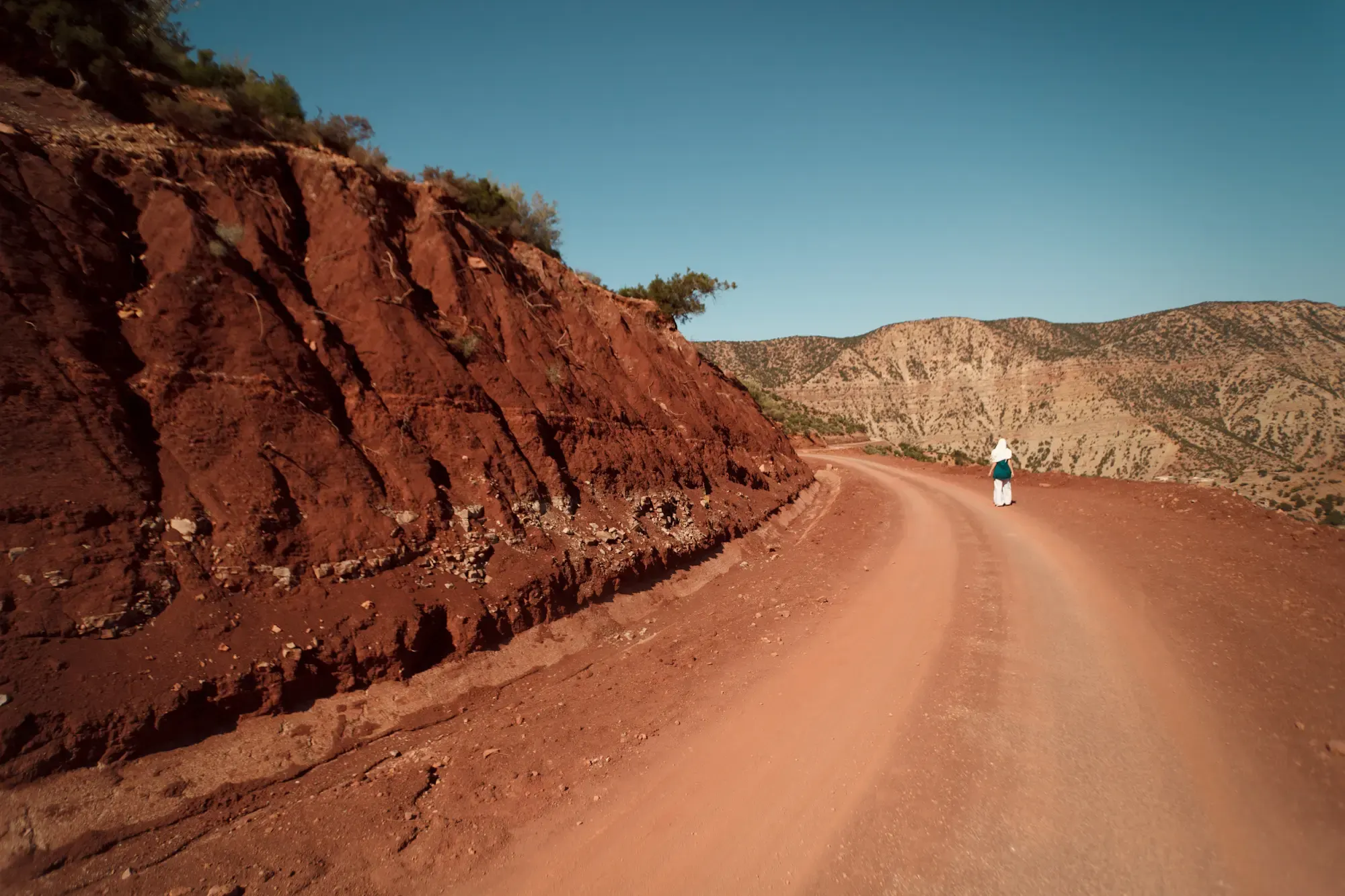 Rote Felsschlucht mit Strasse und gehender Person, Morocco Experience