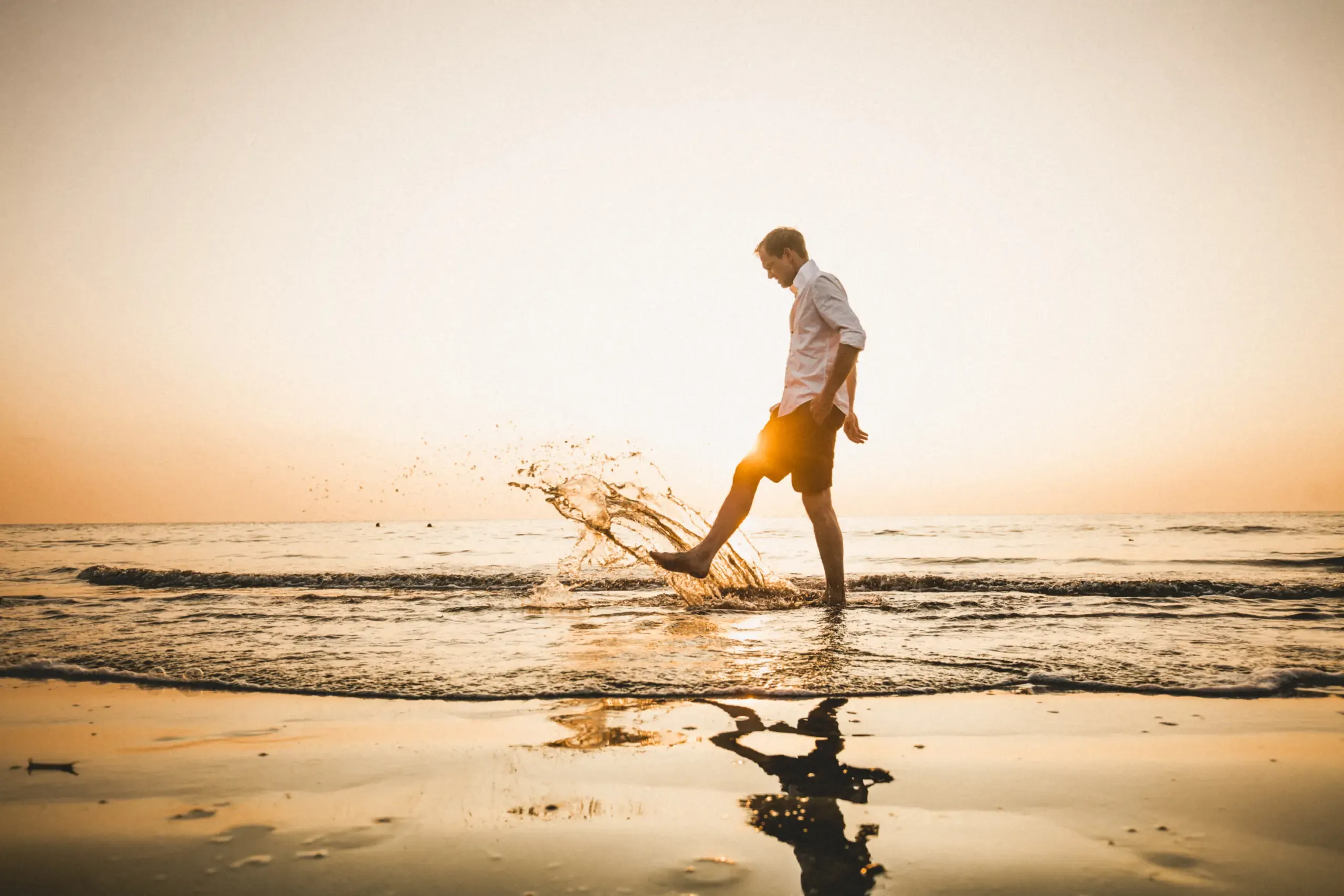 Person geht durch spritzendes Wasser im Sonnenuntergang