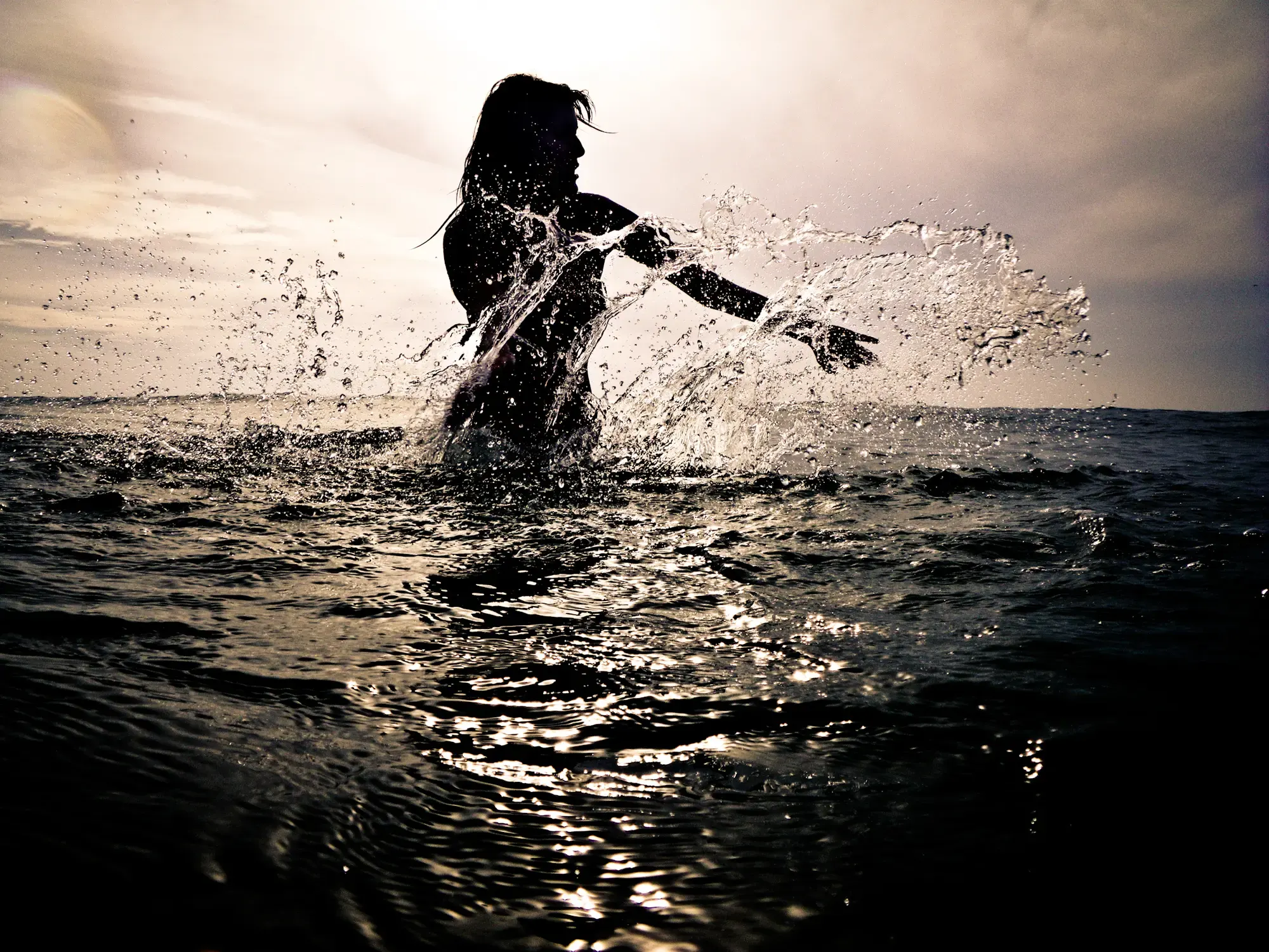 Silhouette einer Person beim Wasserspritzen am Meer in Marokko