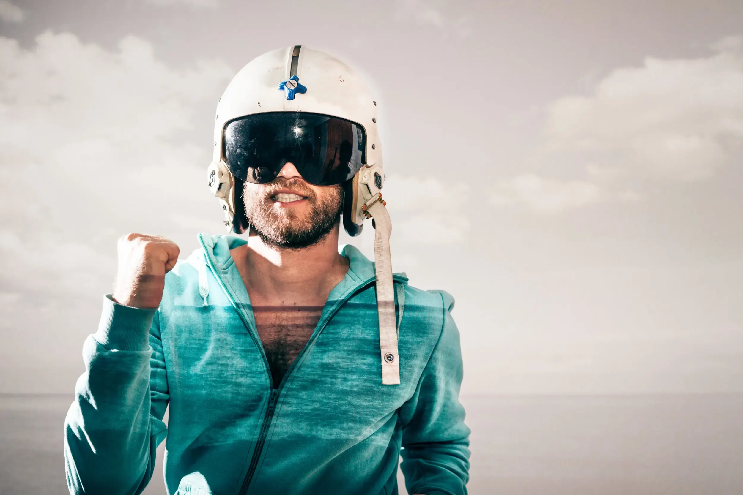 Mann mit Astronautenhelm und erhobener Faust vor Wolkenhimmel