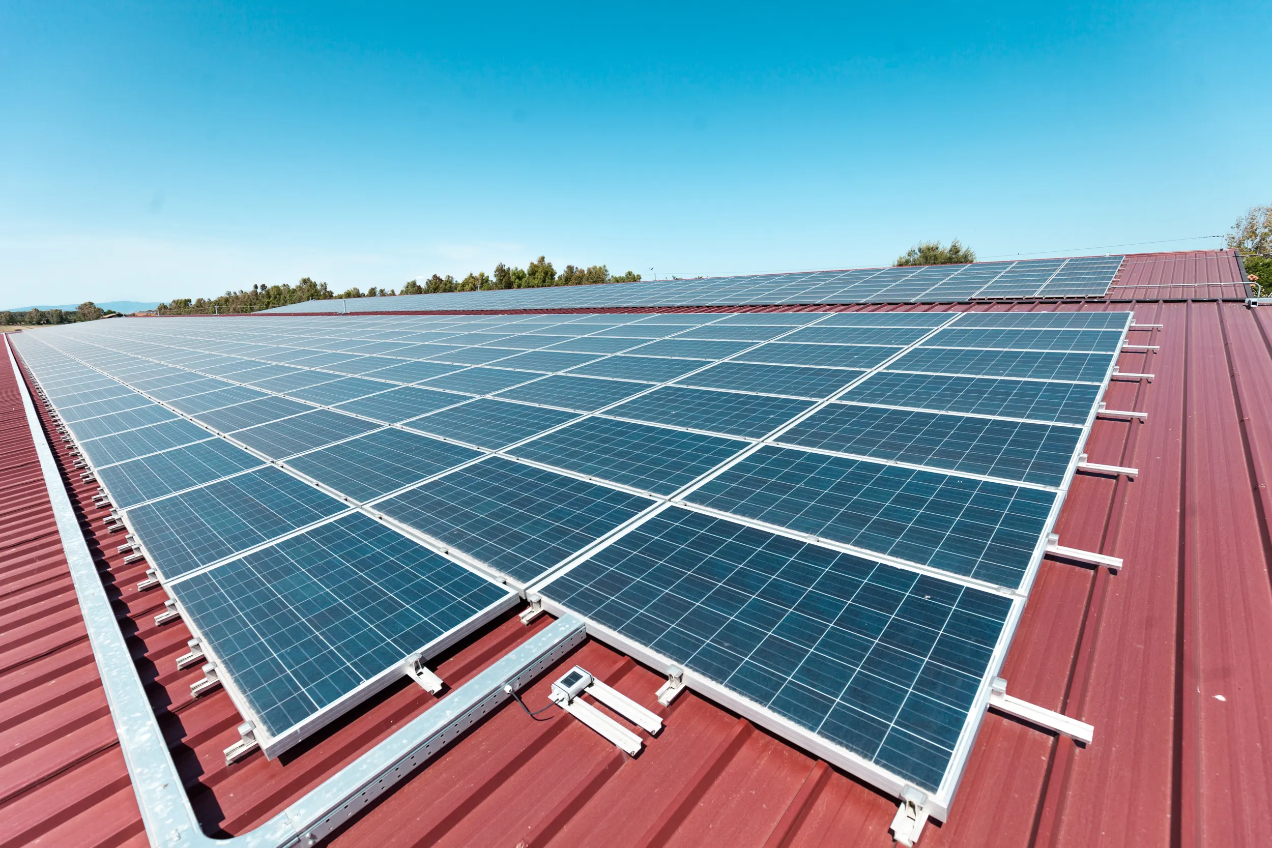 Solarpanels auf rotem Dach vor blauem Himmel, Sardasol