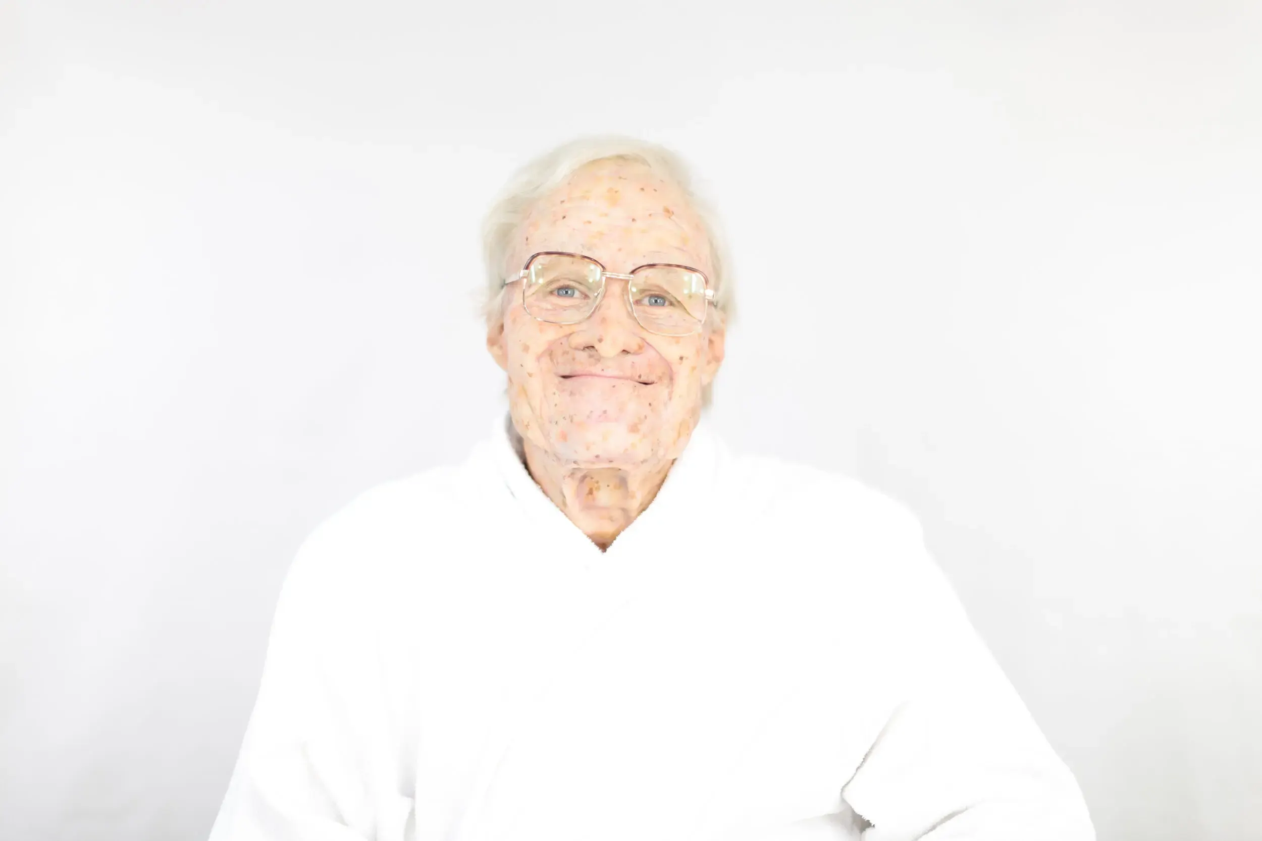 Bühnenfoto aus „Die schönsten Sterbeszenen der Oper“: älterer Mann mit Brille in weissem Gewand