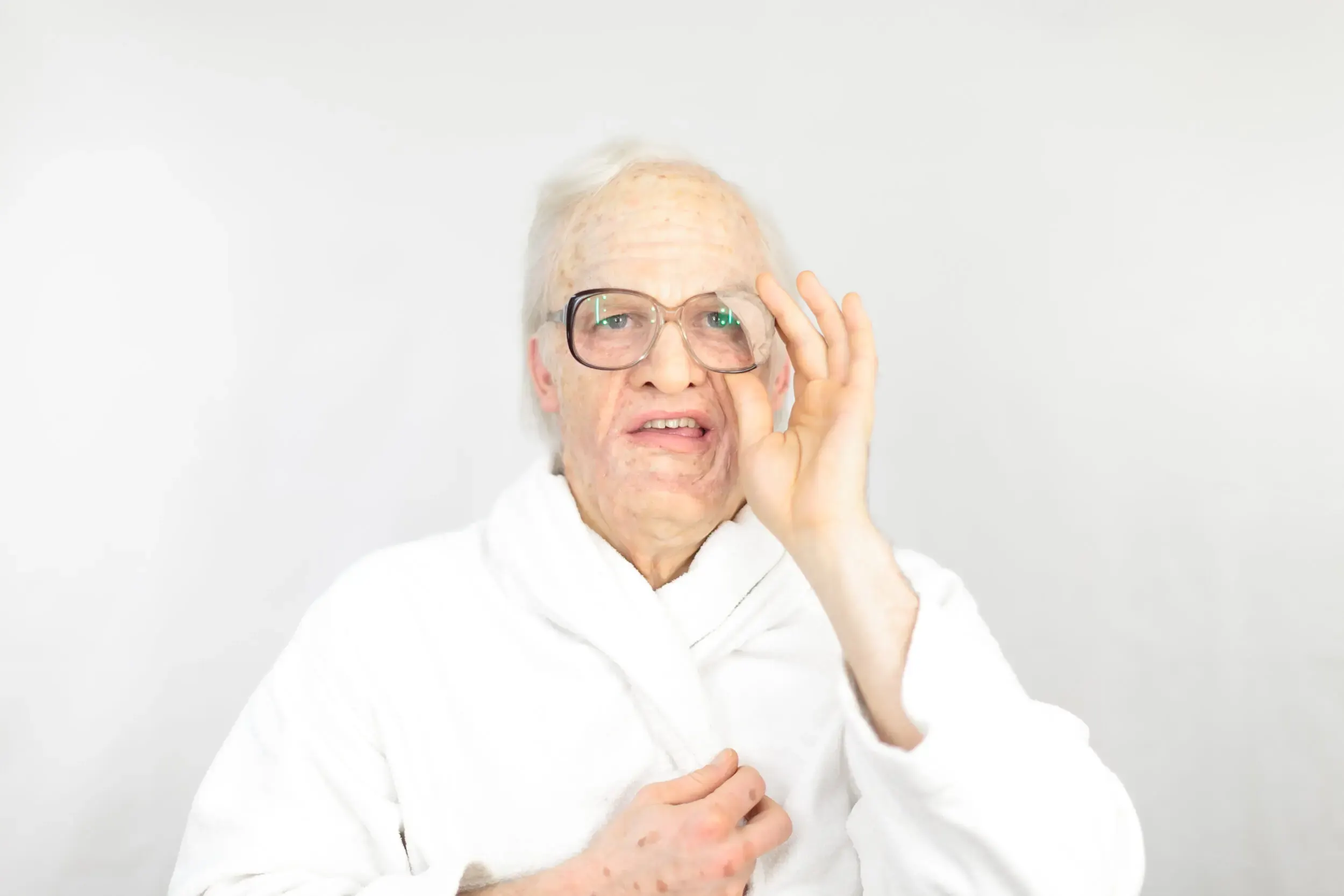 Bühnenfoto aus „Die schönsten Sterbeszenen der Oper“: älterer Mann mit Brille, Hand am Ohr