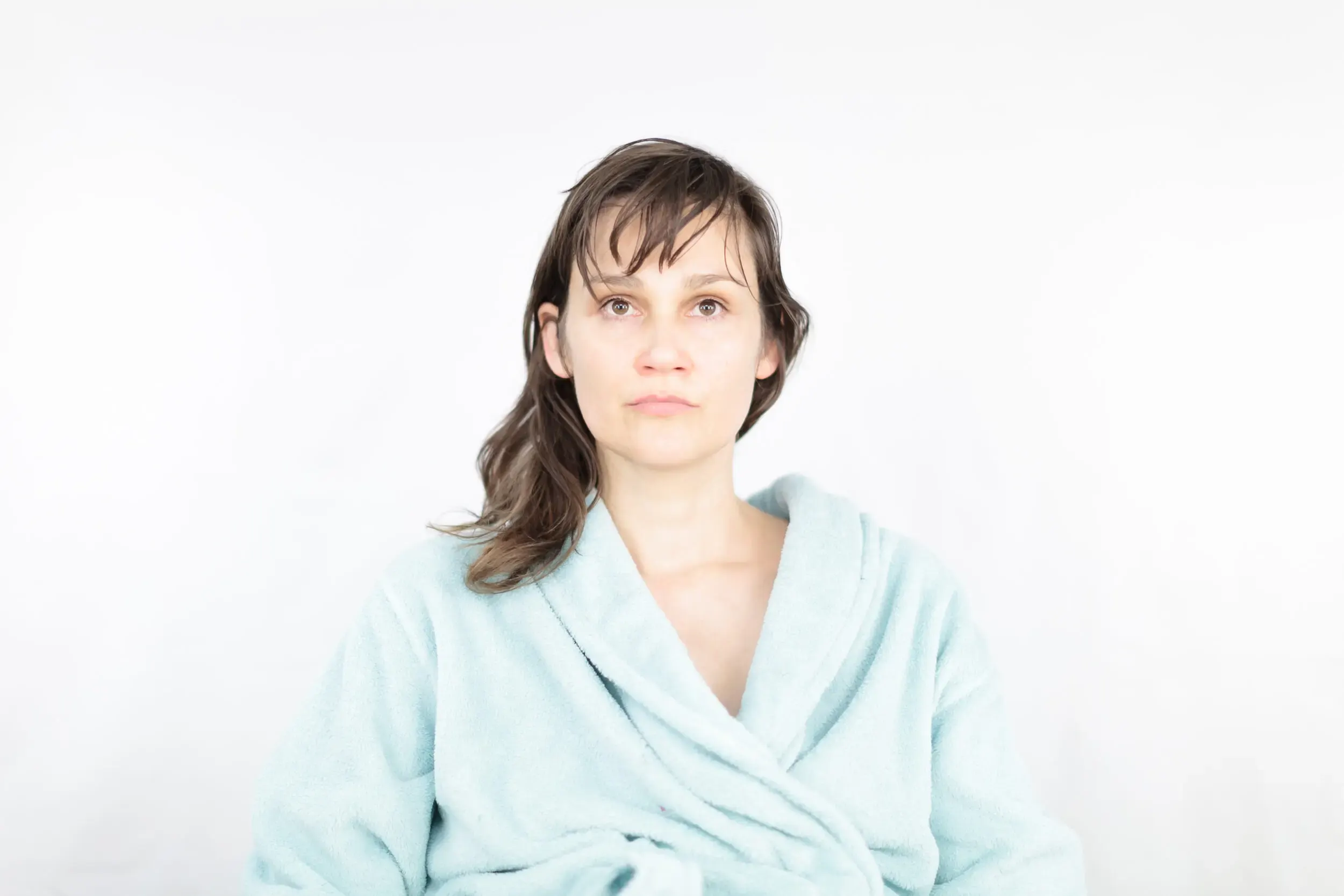 Portrait einer Frau im Bademantel vor weissem Hintergrund