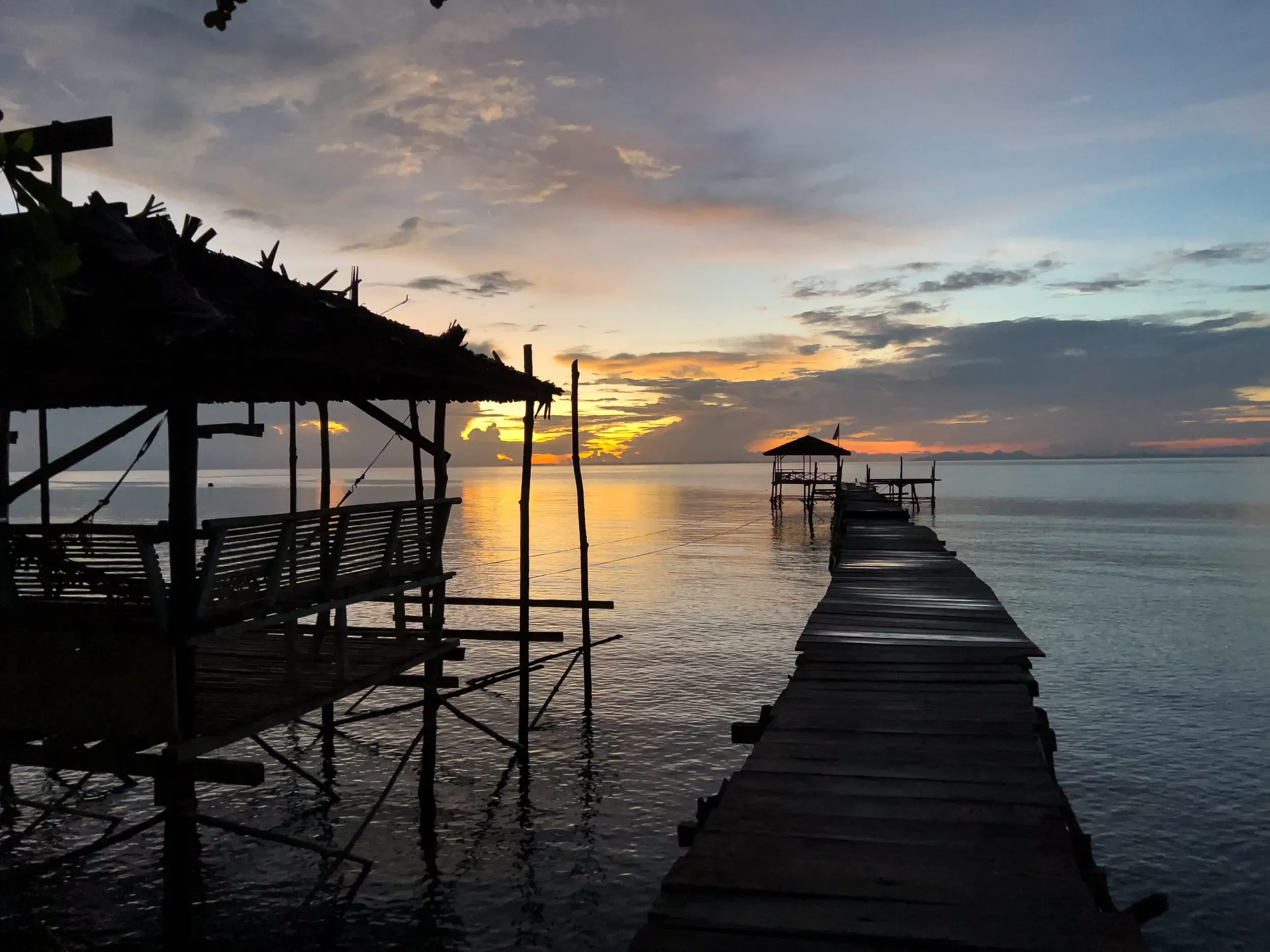 Holzsteg über dem Wasser bei Sonnenuntergang, Sulawesi