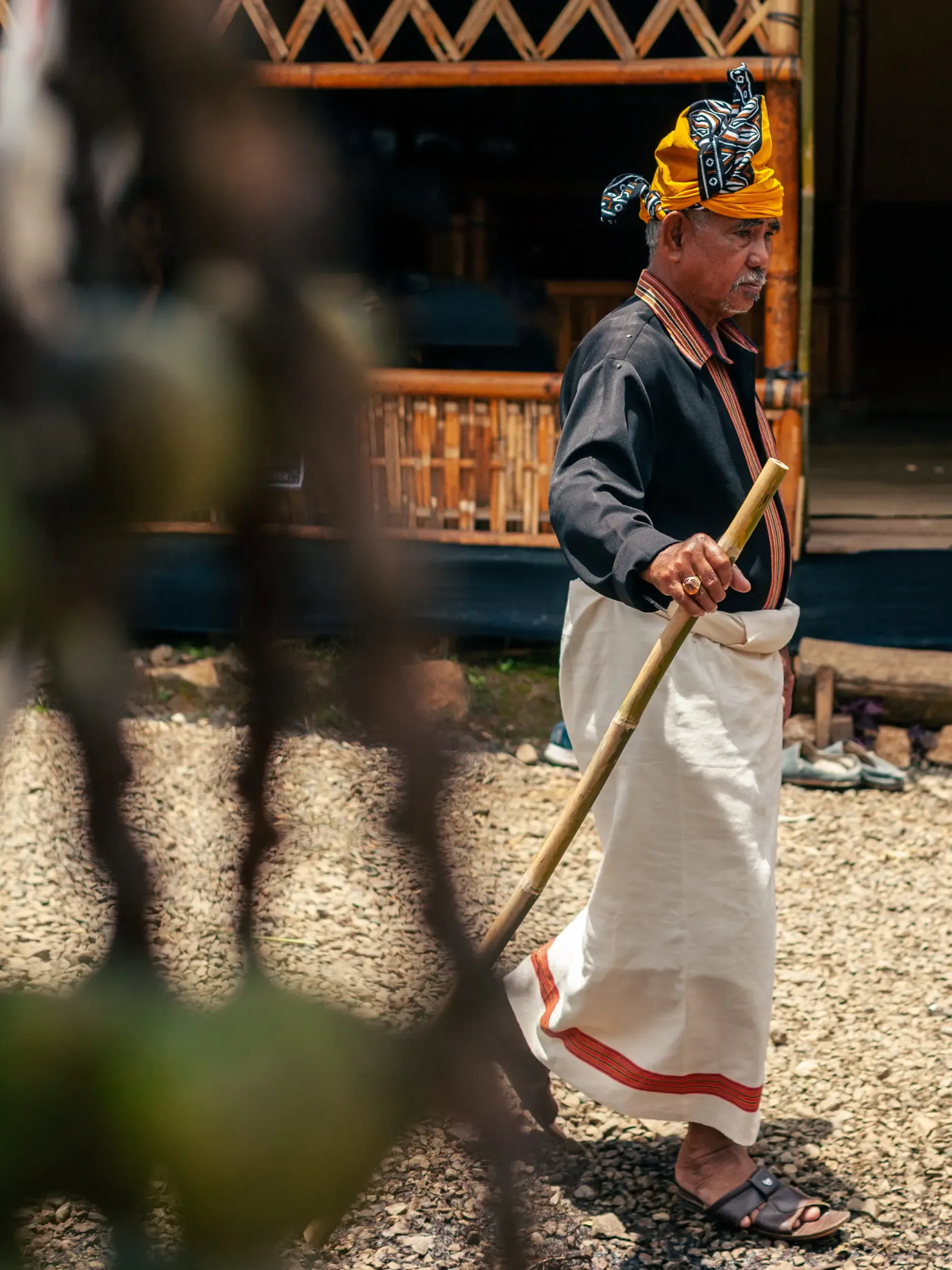 Person in traditioneller Kleidung mit Gehstock, Sulawesi