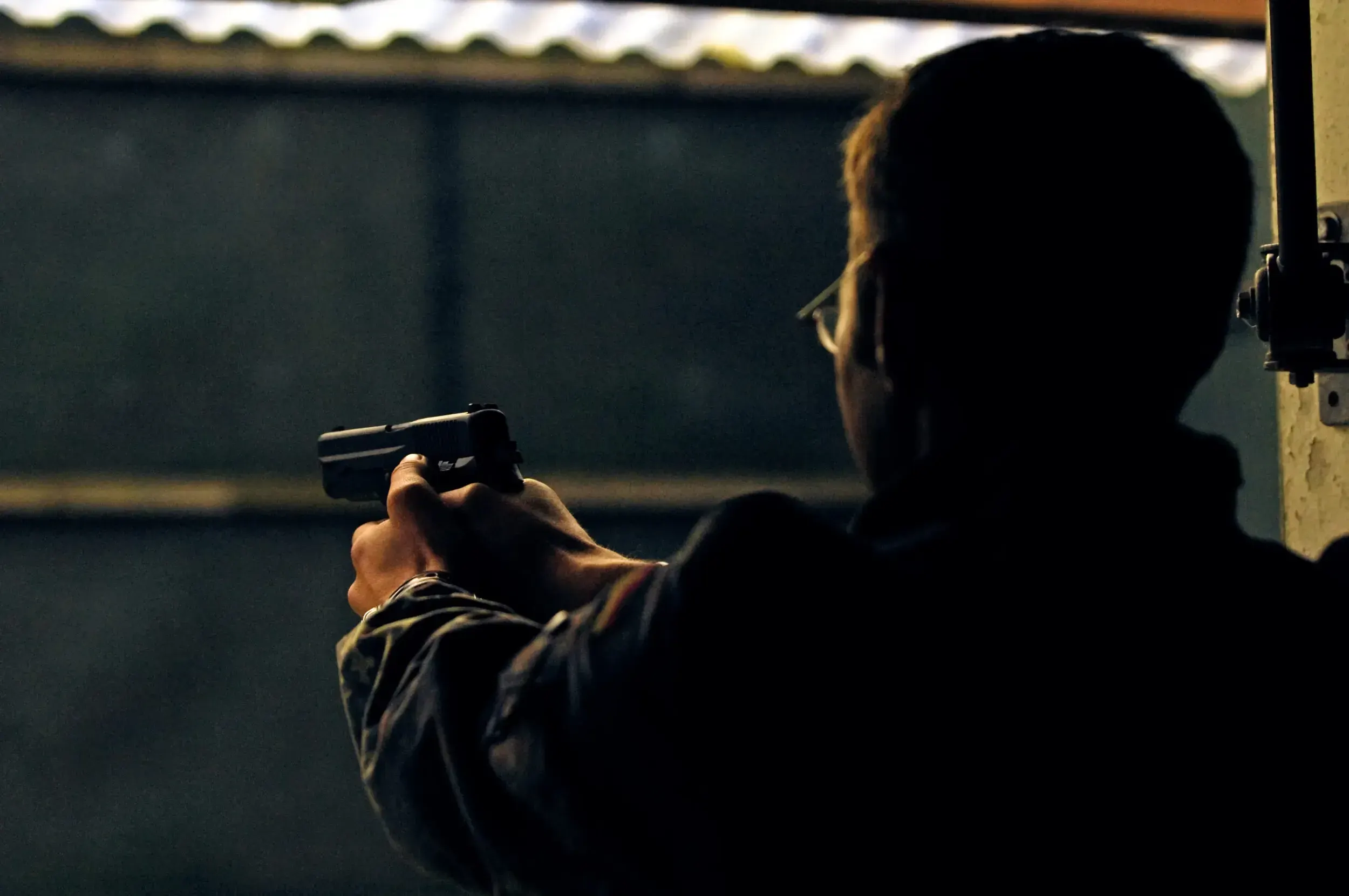 Silhouette of a soldier aiming a pistol during indoor shooting training.