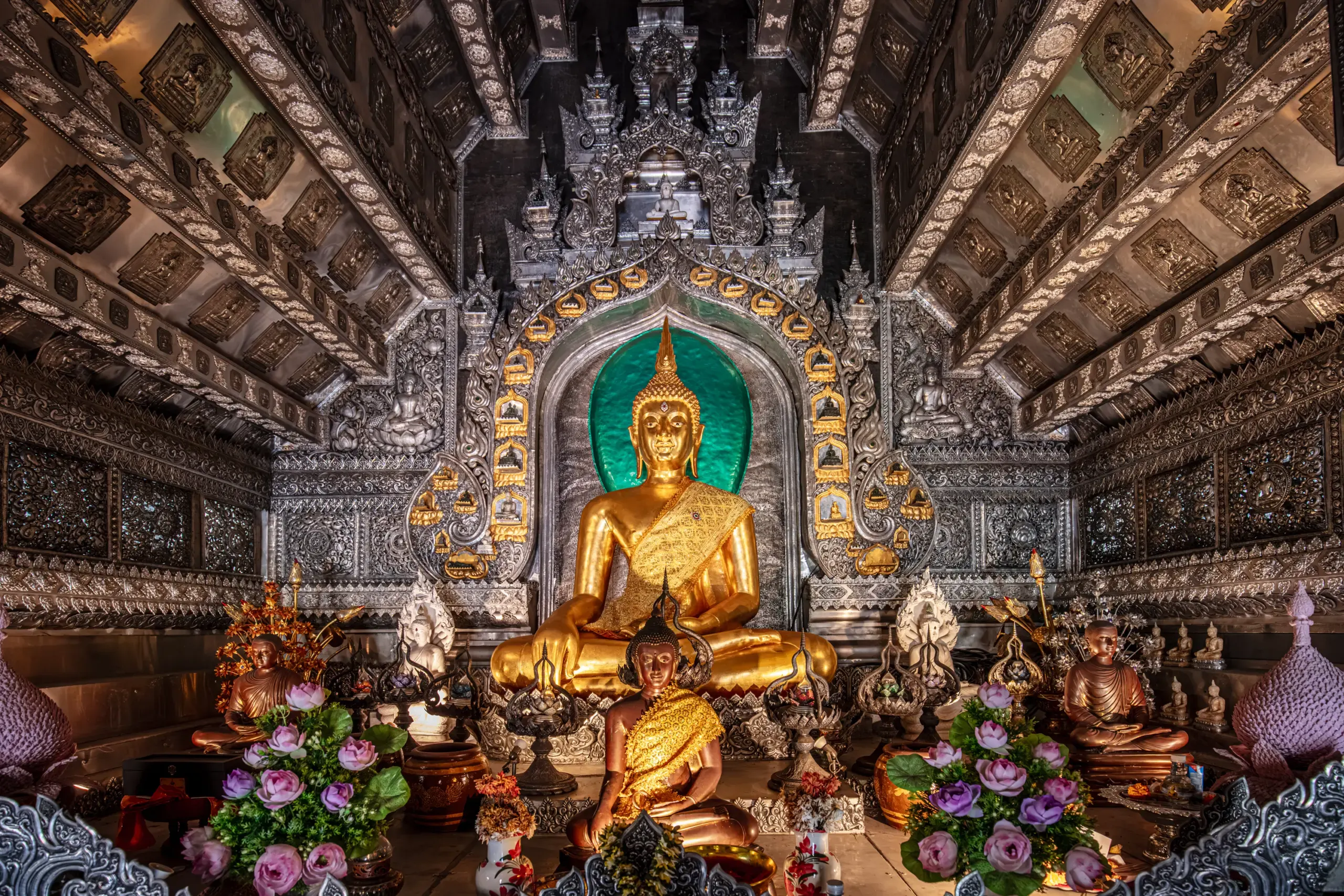Goldene Buddha-Statue im reich verzierten Tempelinnenraum