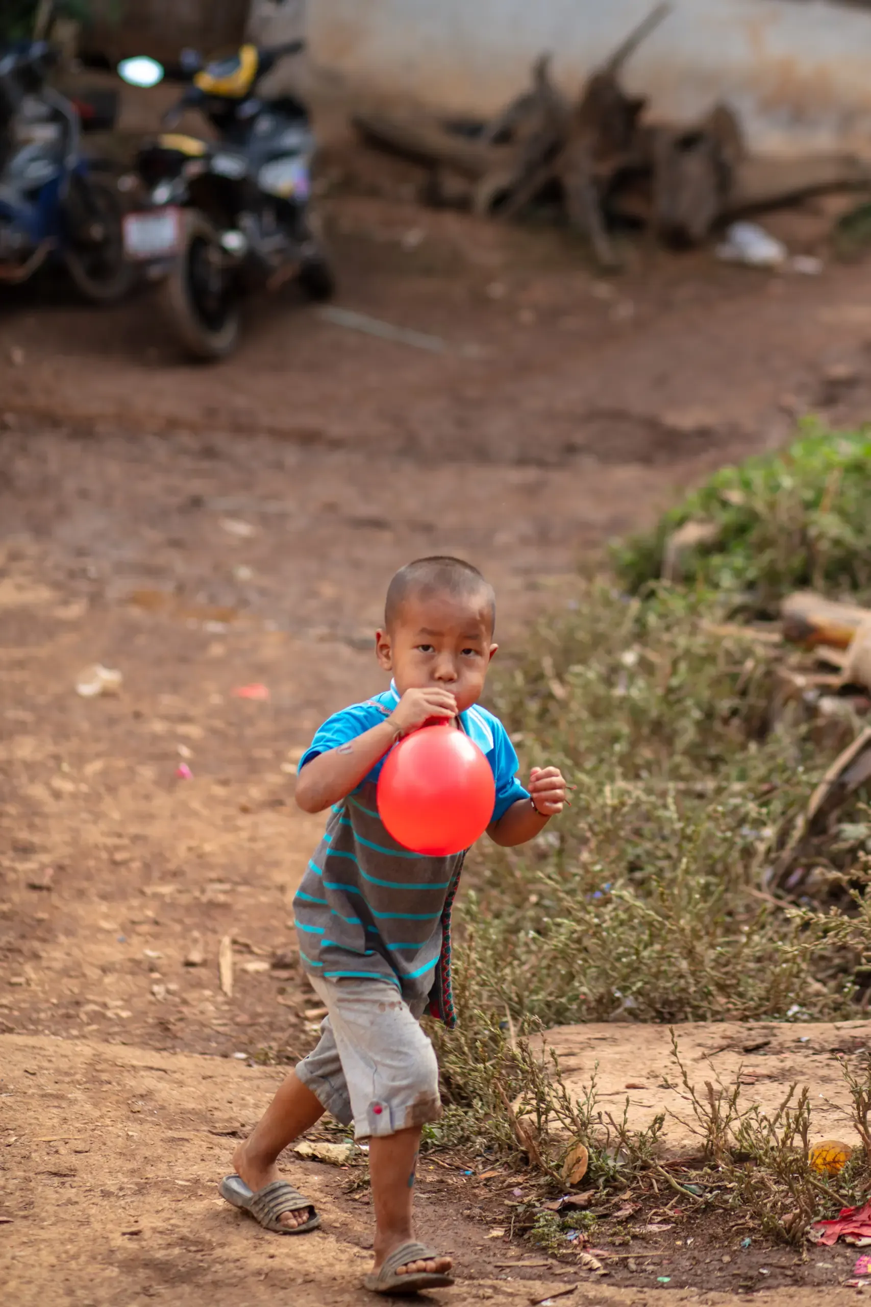Kind läuft mit einem Ballon über einen Feldweg