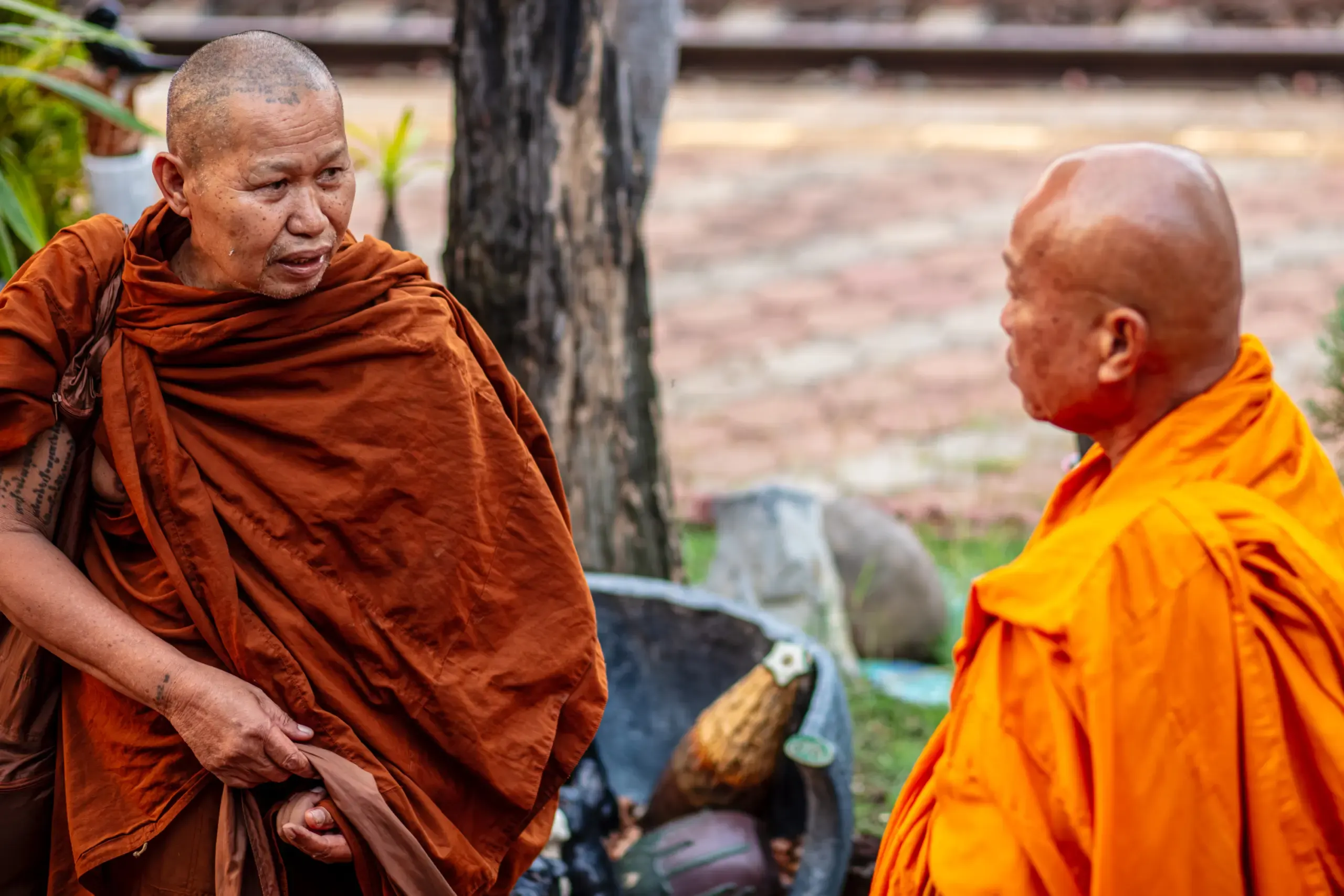 Zwei buddhistische Mönche in orangen Roben im Gespräch