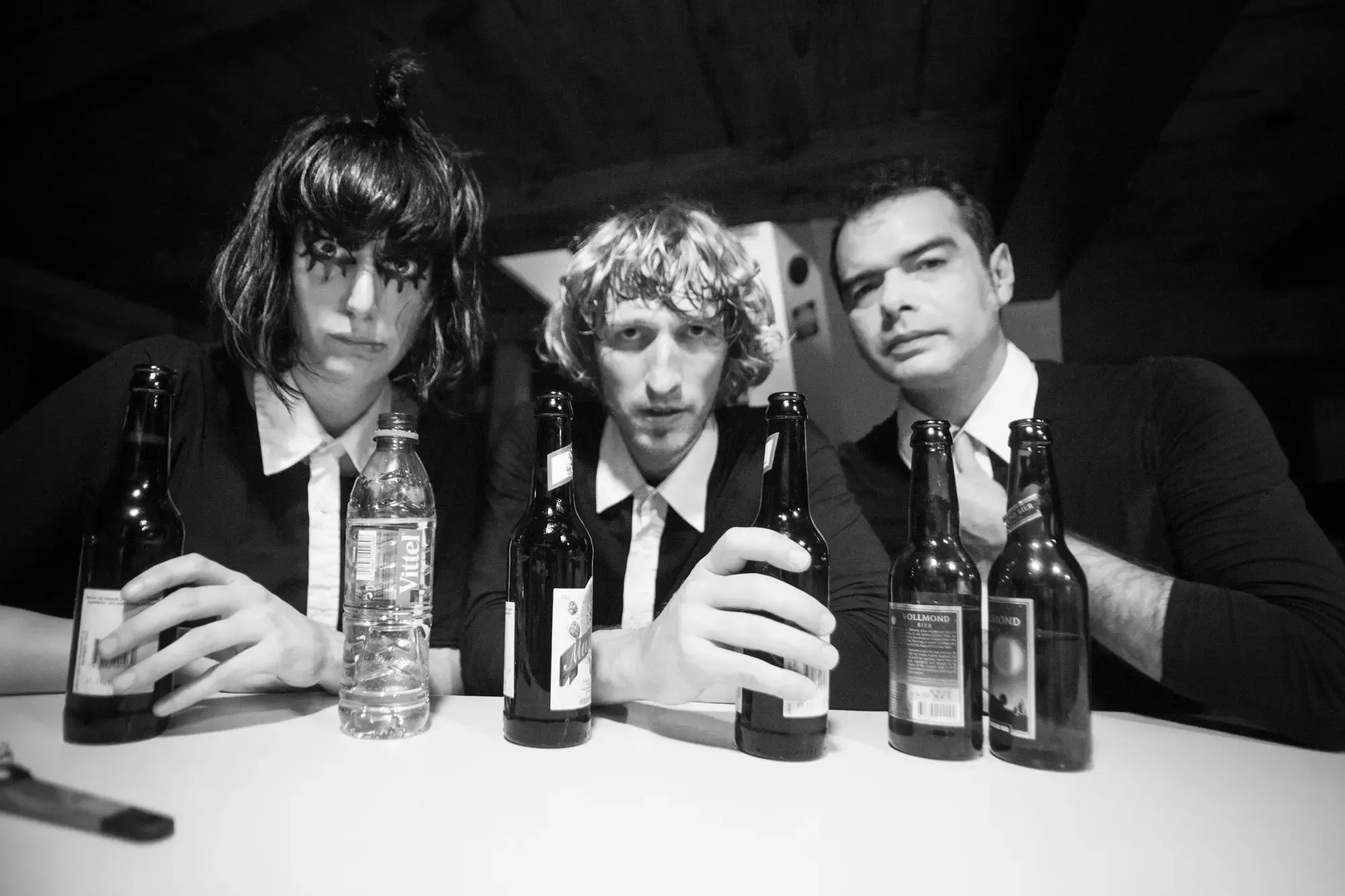 Schwarzweissfoto der Band The Jackets an der Bar mit Bierflaschen