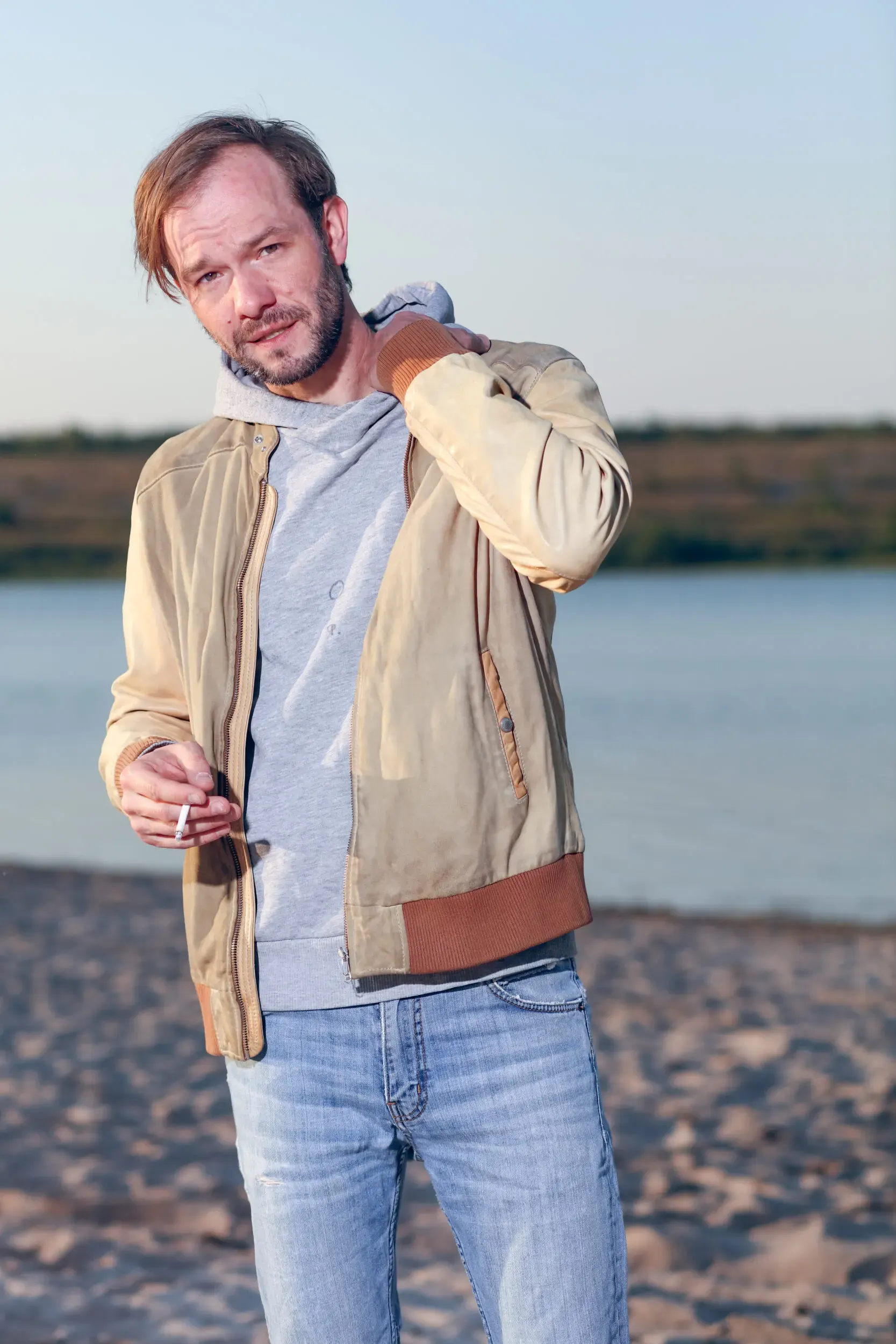 Tim Wildner steht leger gekleidet am Strand