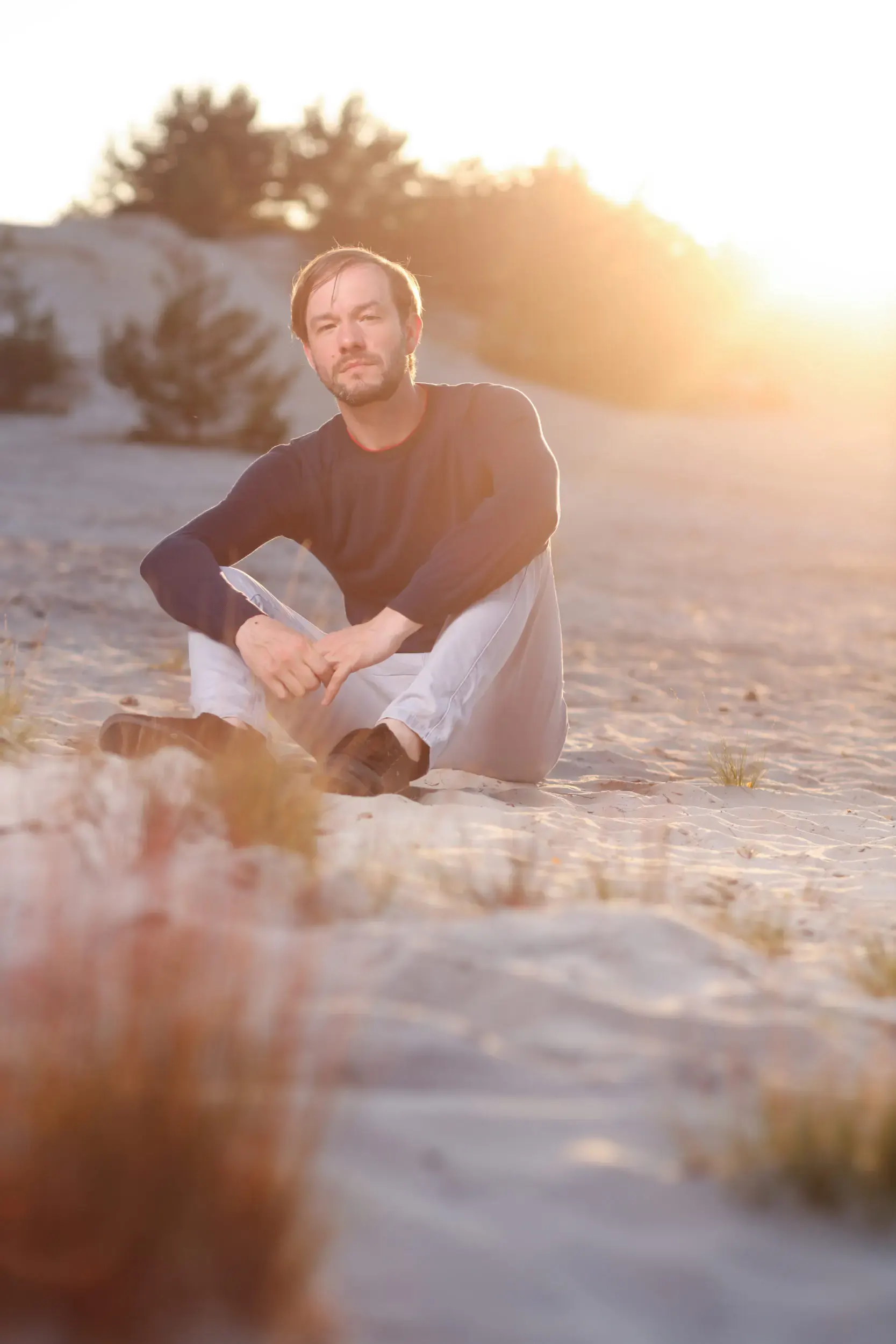 Tim Wildner sitzt im Schneidersitz in den Dünen
