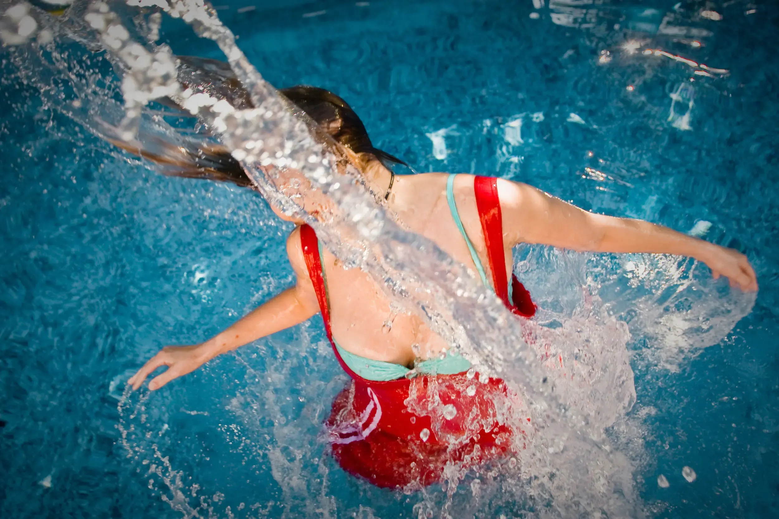 Frau in rotem Kleid schwebt unter Wasser mit ausgestrecktem Bein, under(water) love
