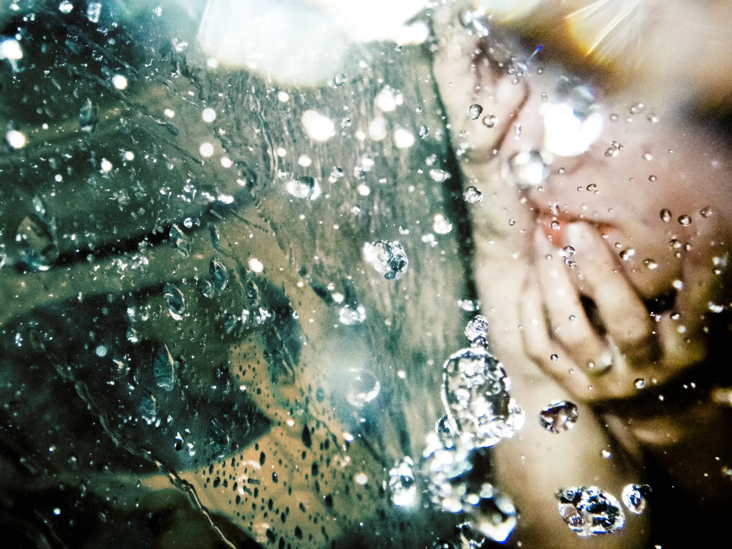 Nahaufnahme einer Hand unter Wasser mit Luftblasen, under(water) love