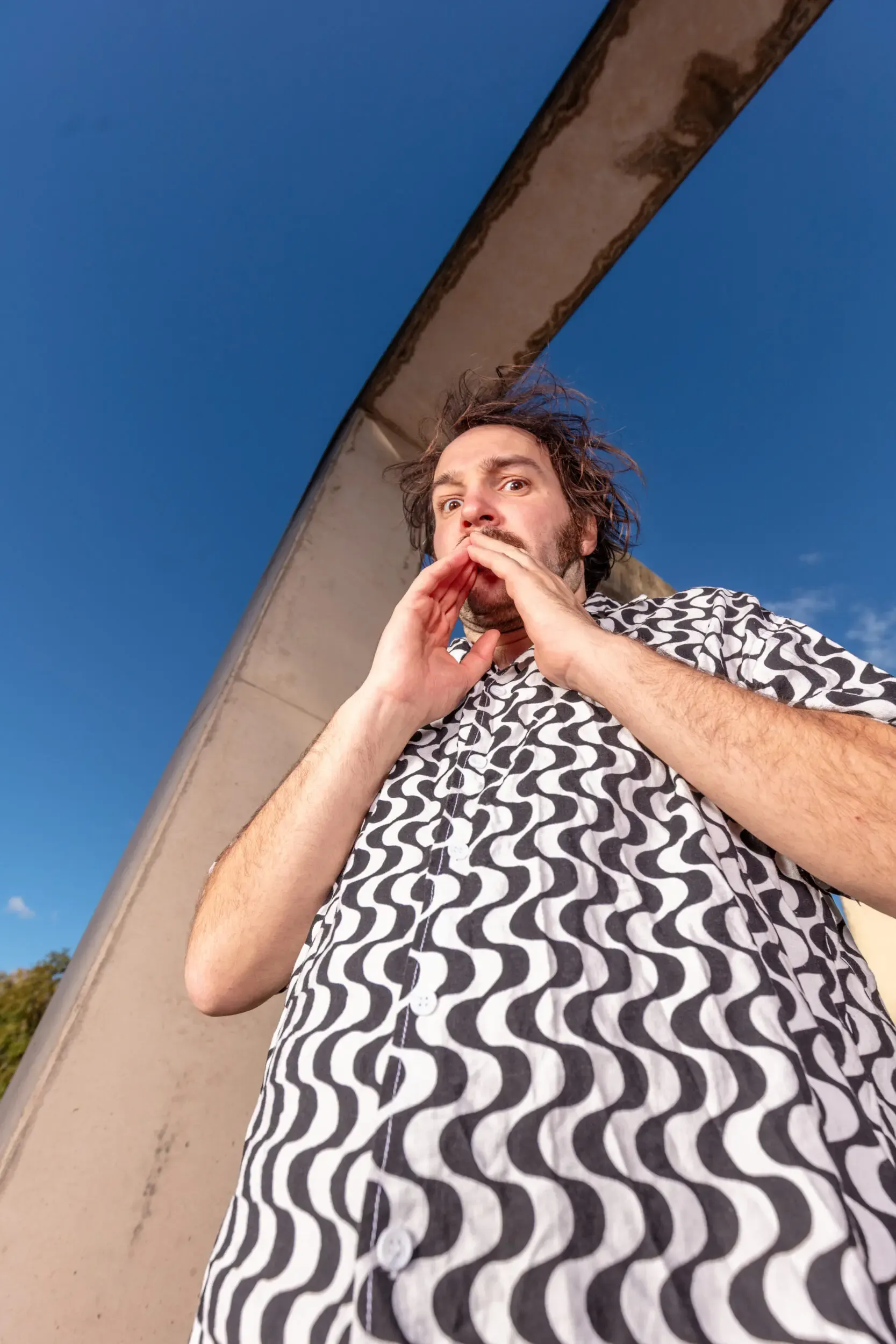 Valerio Moser lehnt schräg an einer Wand vor blauem Himmel