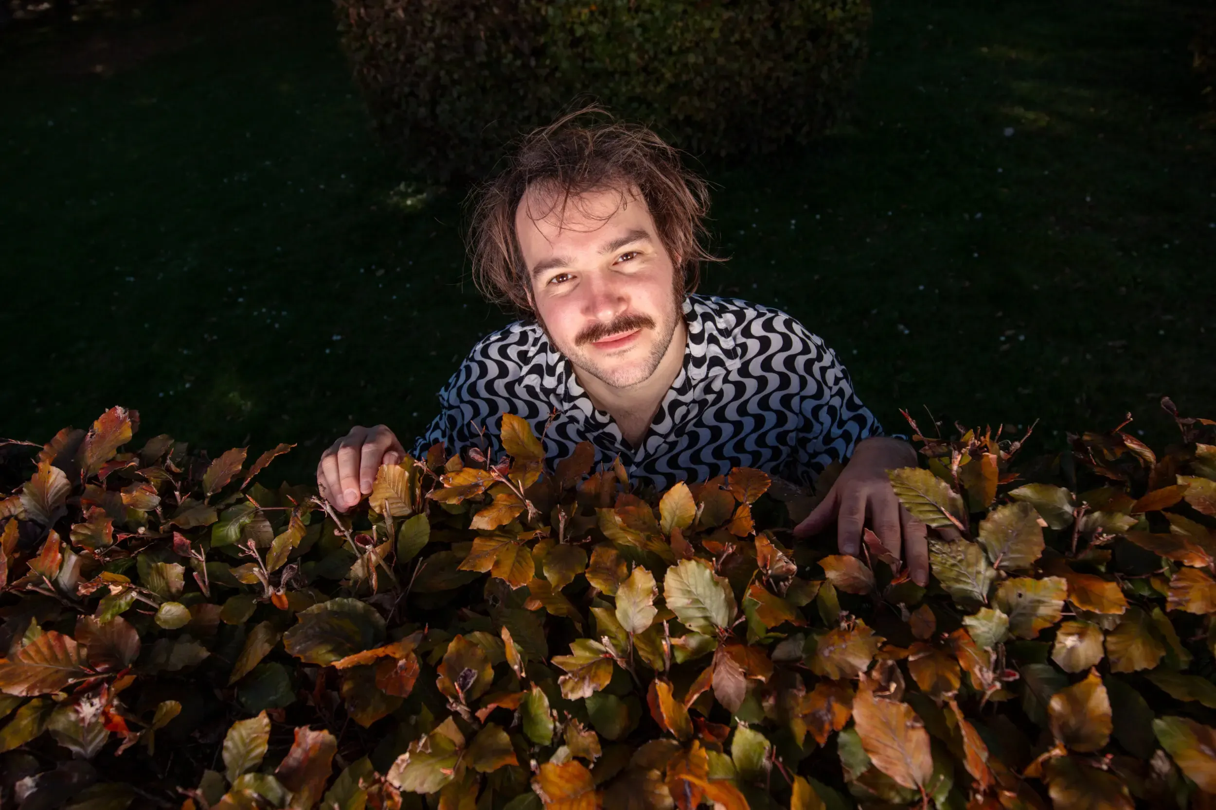 Valerio Moser sitzt in herbstlichem Laub