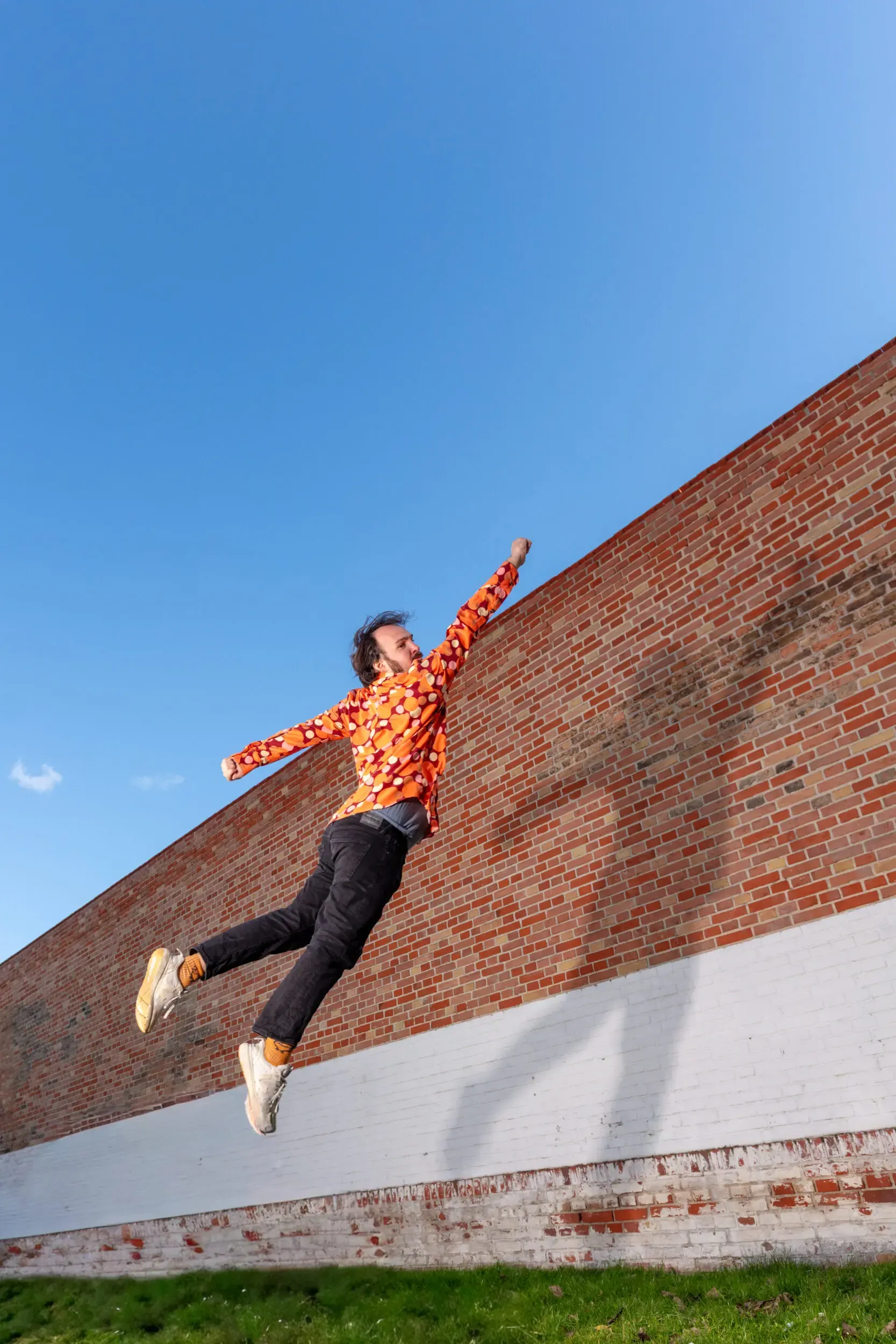 Valerio Moser springt vor einer schrägen Backsteinwand