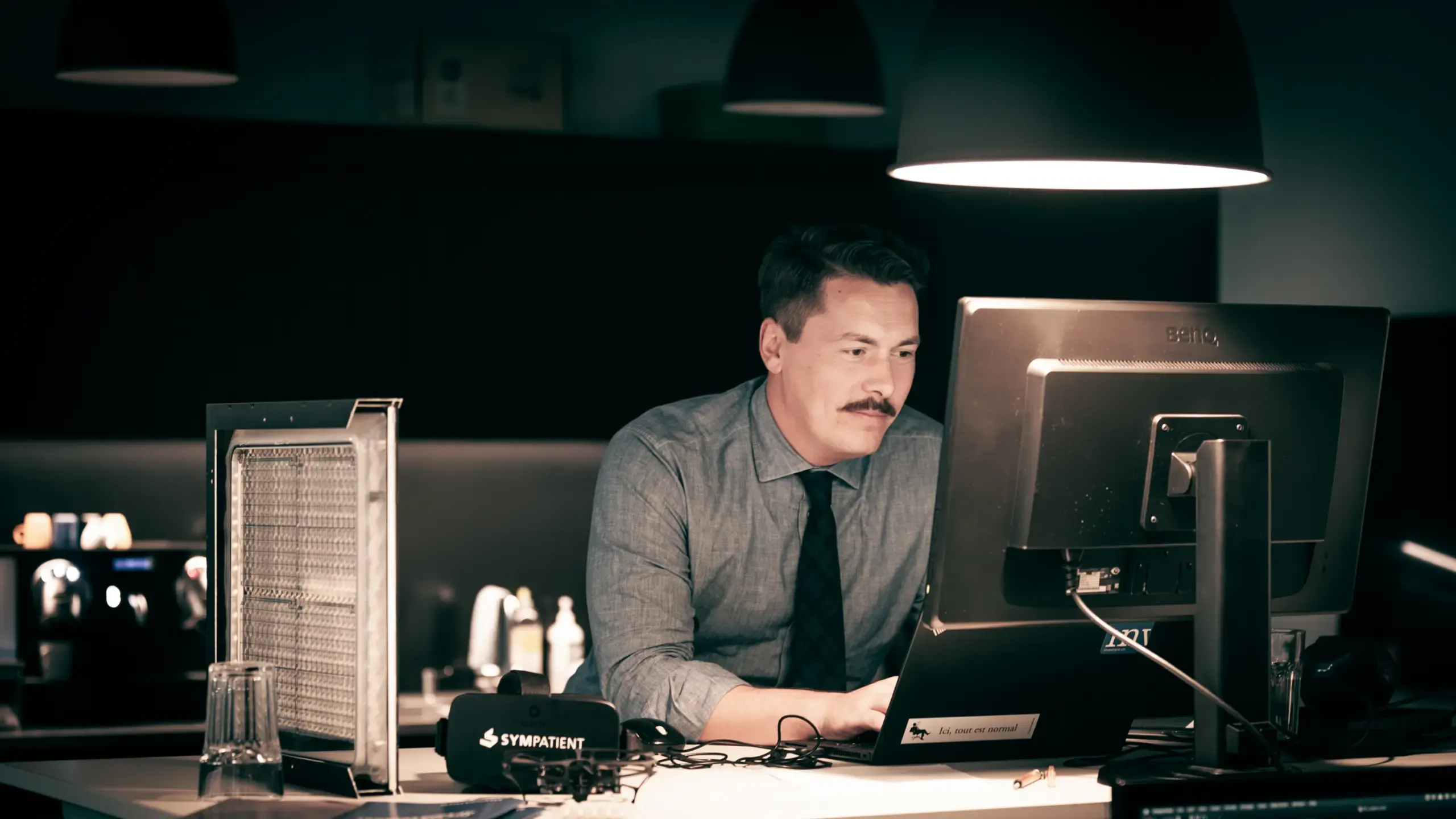 Mann mit Schnurrbart arbeitet abends konzentriert am Bildschirm im Büro, Verve Ventures