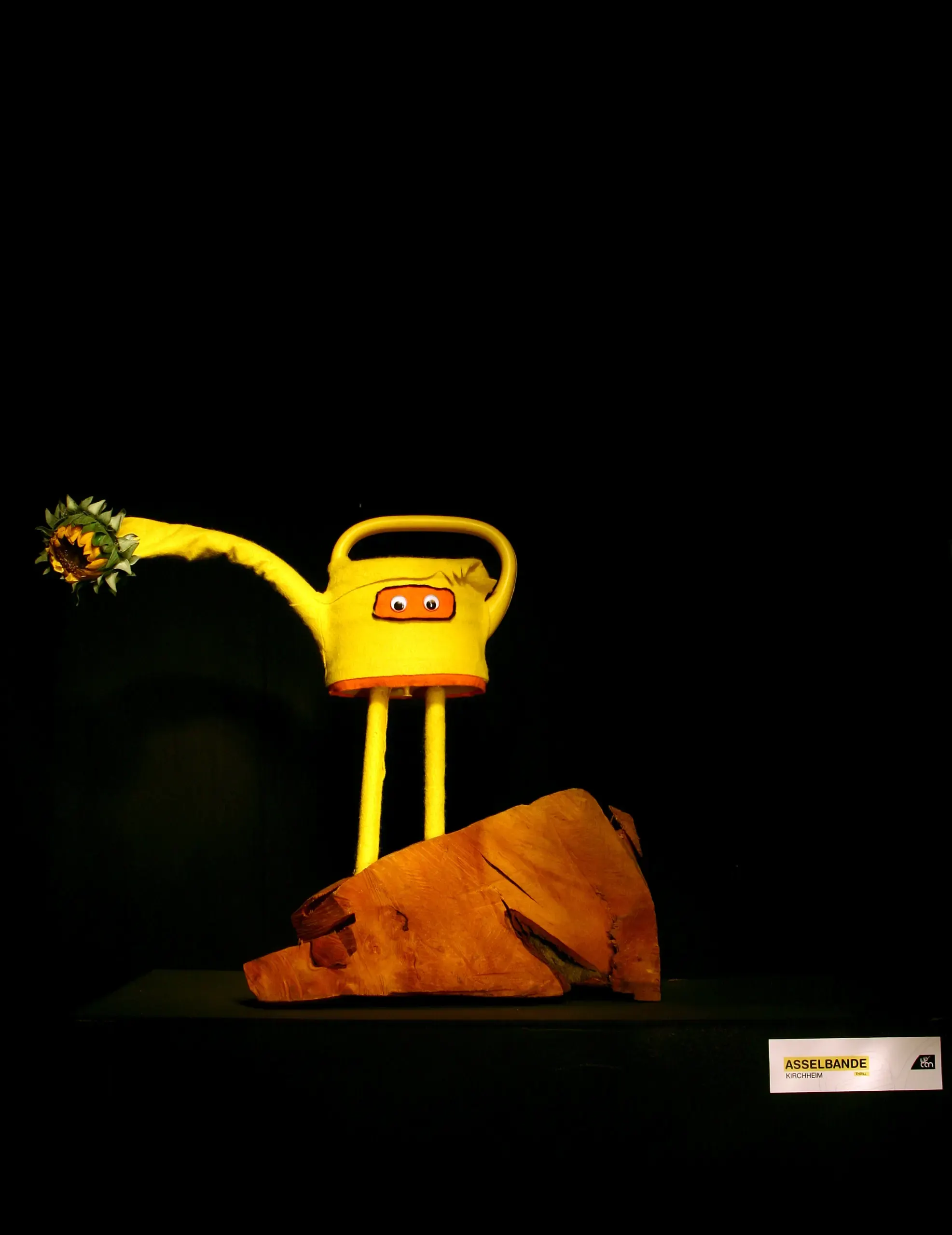 „Can“-Skulptur mit Blumen auf orangem Sockel von Asselbande