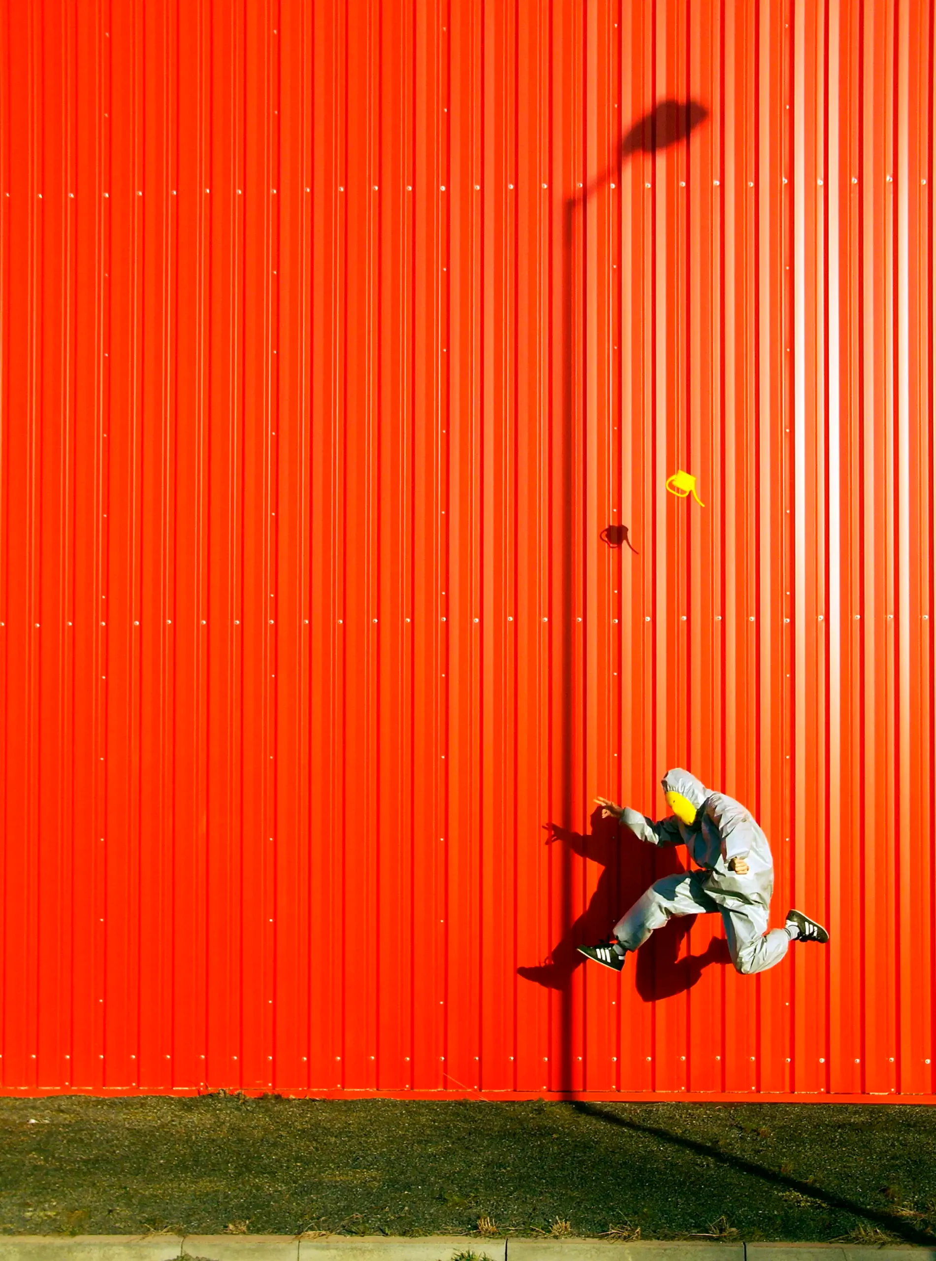 Person im Schutzanzug mit Giesskanne vor einer roten Wand
