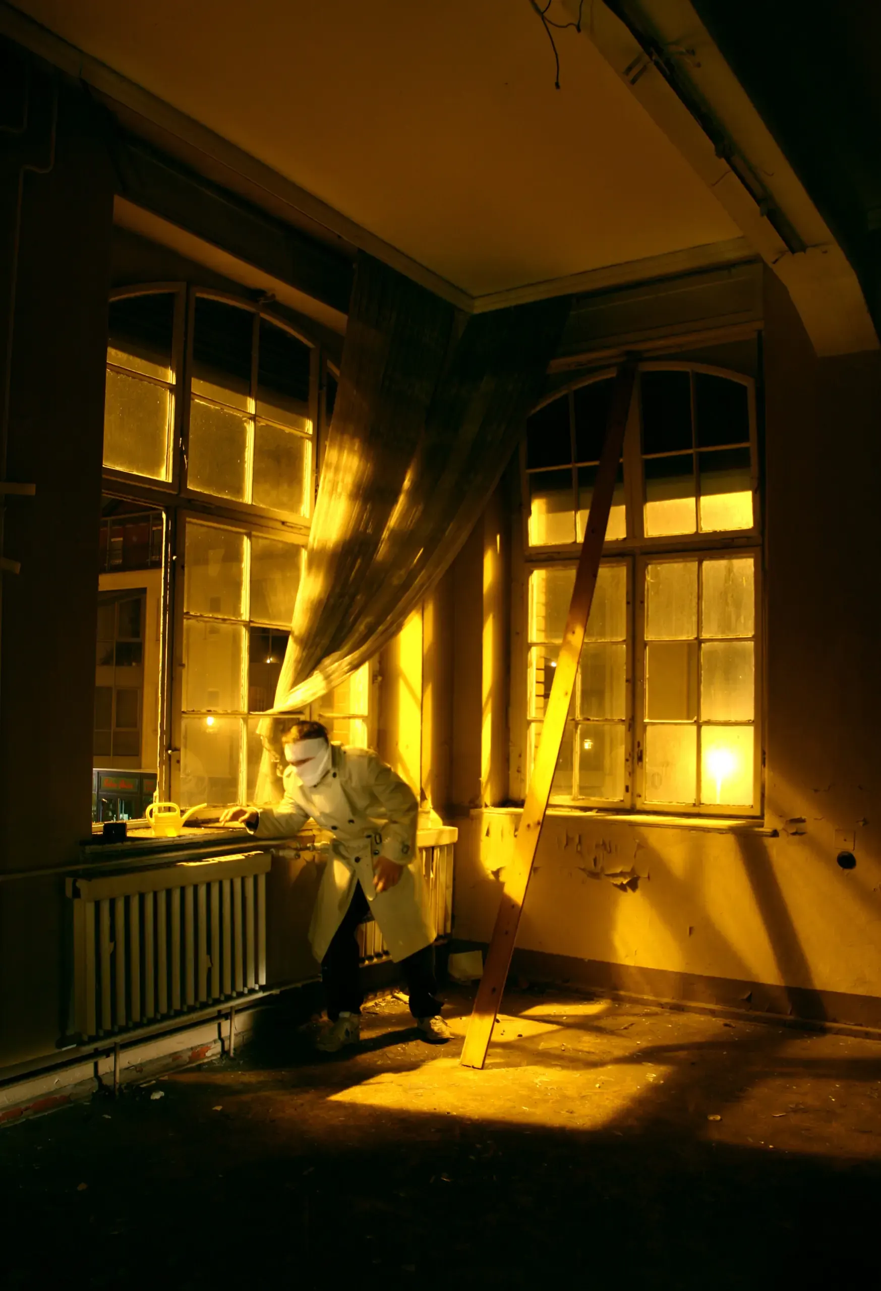 Person sitzt im Gegenlicht an einem Fenster neben einer Can-Figur